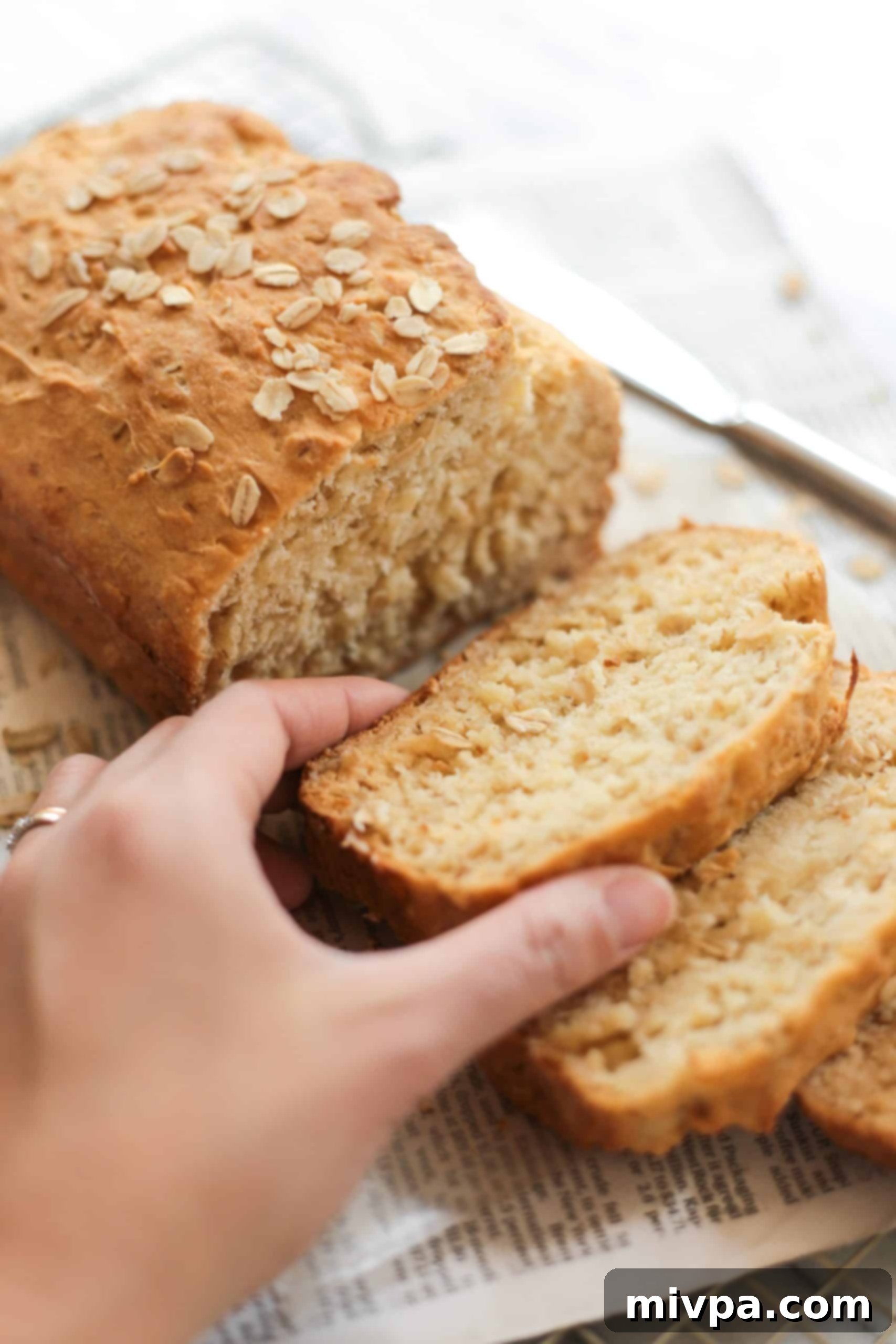 A hand reaching for a warm slice of gluten-free oat bread, inviting indulgence.