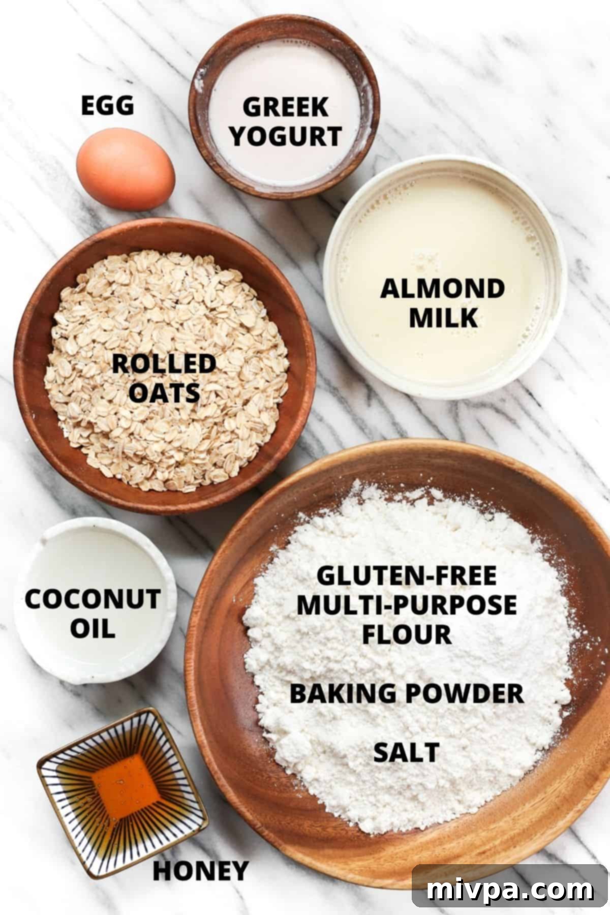 Labelled ingredients for honey oat bread recipe, neatly laid out on a marble board.