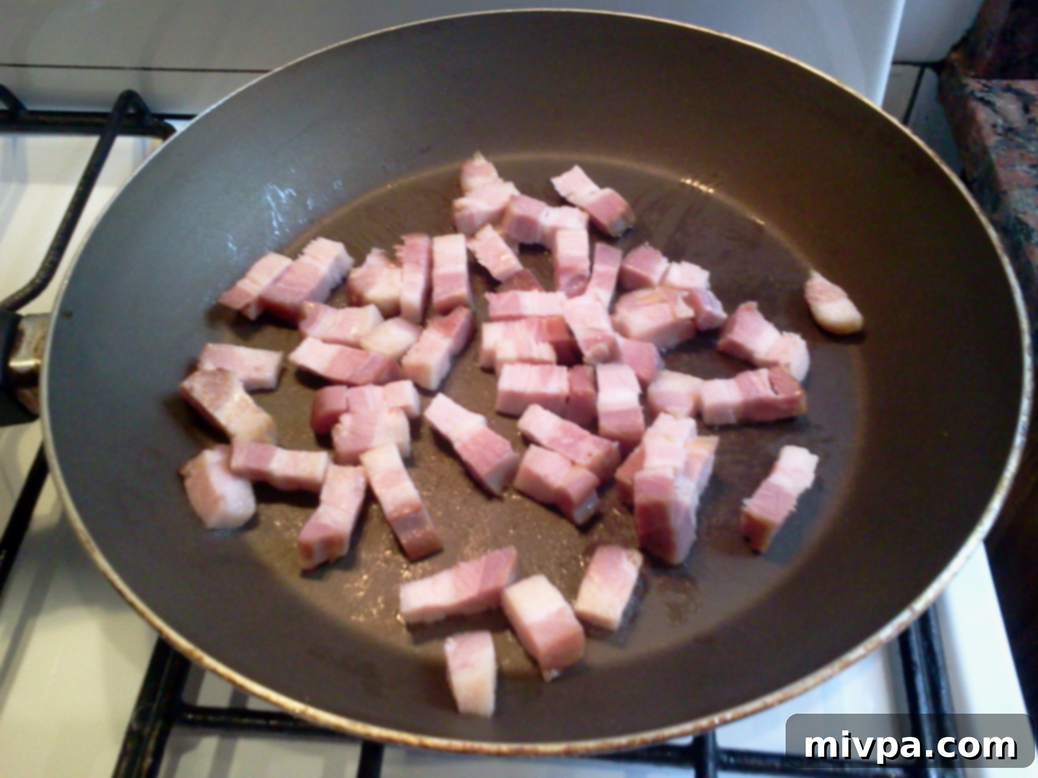 Bacon strips sizzling gently in a pan, releasing their flavorful fat.