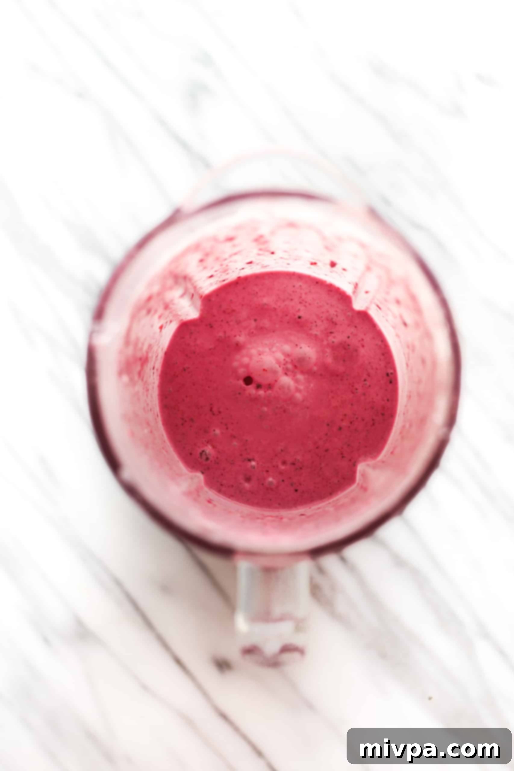 A blender containing a thick, bright pink, blended liquid mixture of berries and yogurt.