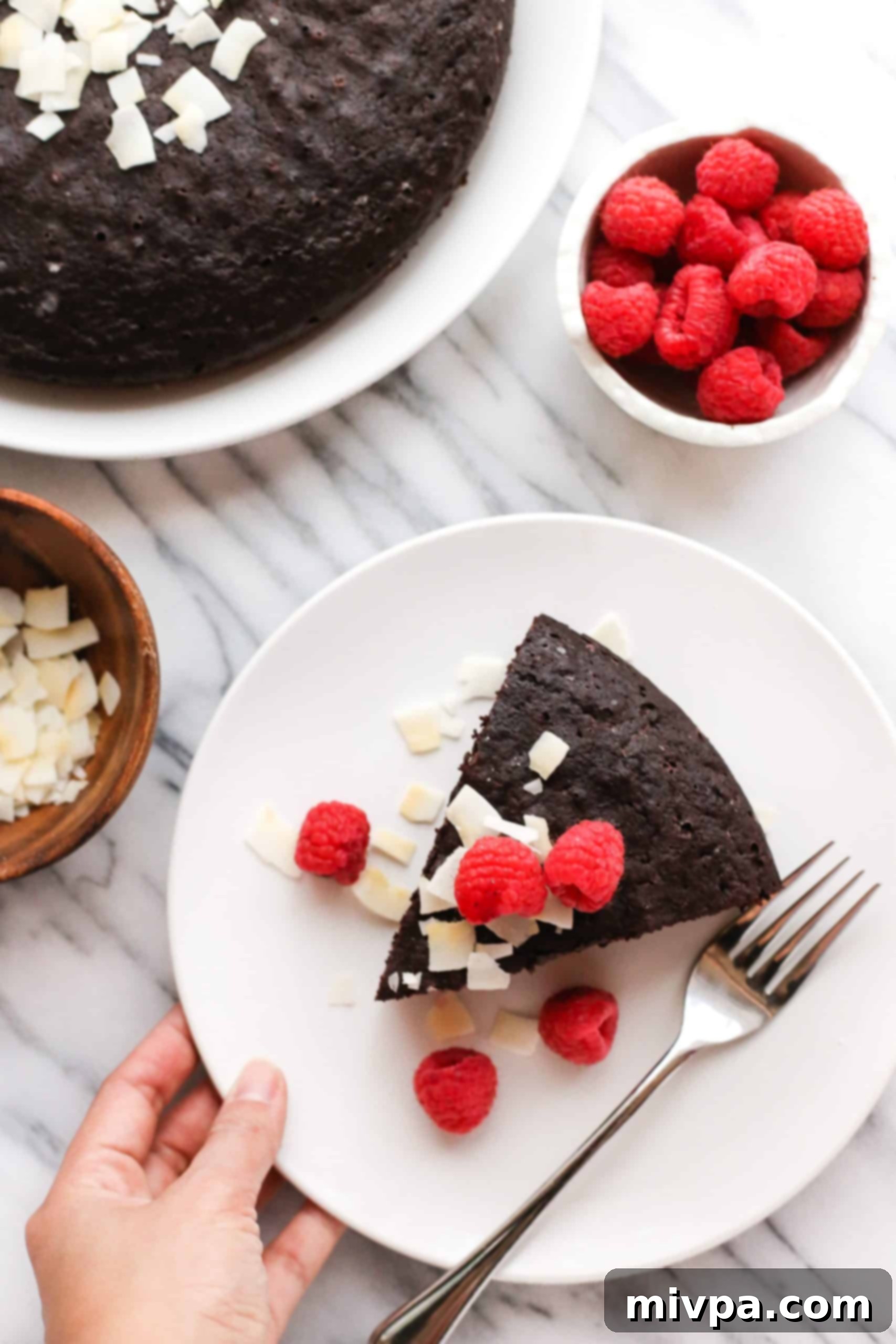 Coconut Flour Chocolate Cake (Gluten-Free, Dairy-Free) Hand holding a plate with a slice of coconut flour chocolate cake.