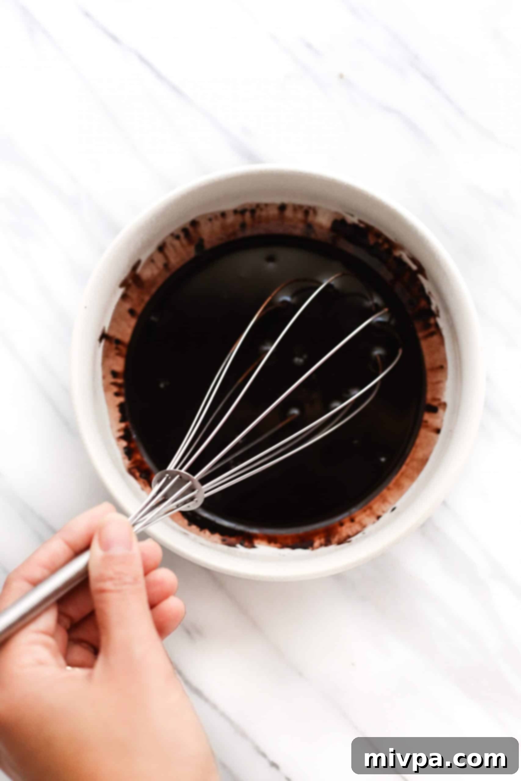 Coconut Flour Chocolate Cake (Gluten-Free, Dairy-Free) Mixing a chocolate mixture in a white bowl.