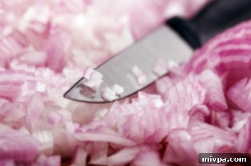 A sharp knife slicing through an onion, illustrating a key technique for tear-free chopping.