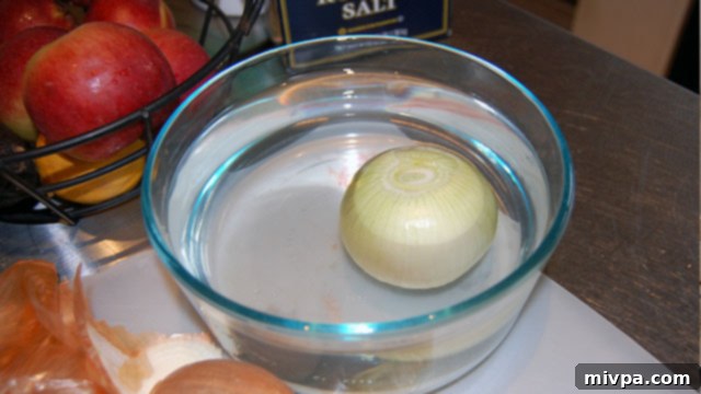 Onion halves soaking in a bowl of water, demonstrating a method to prevent tears.