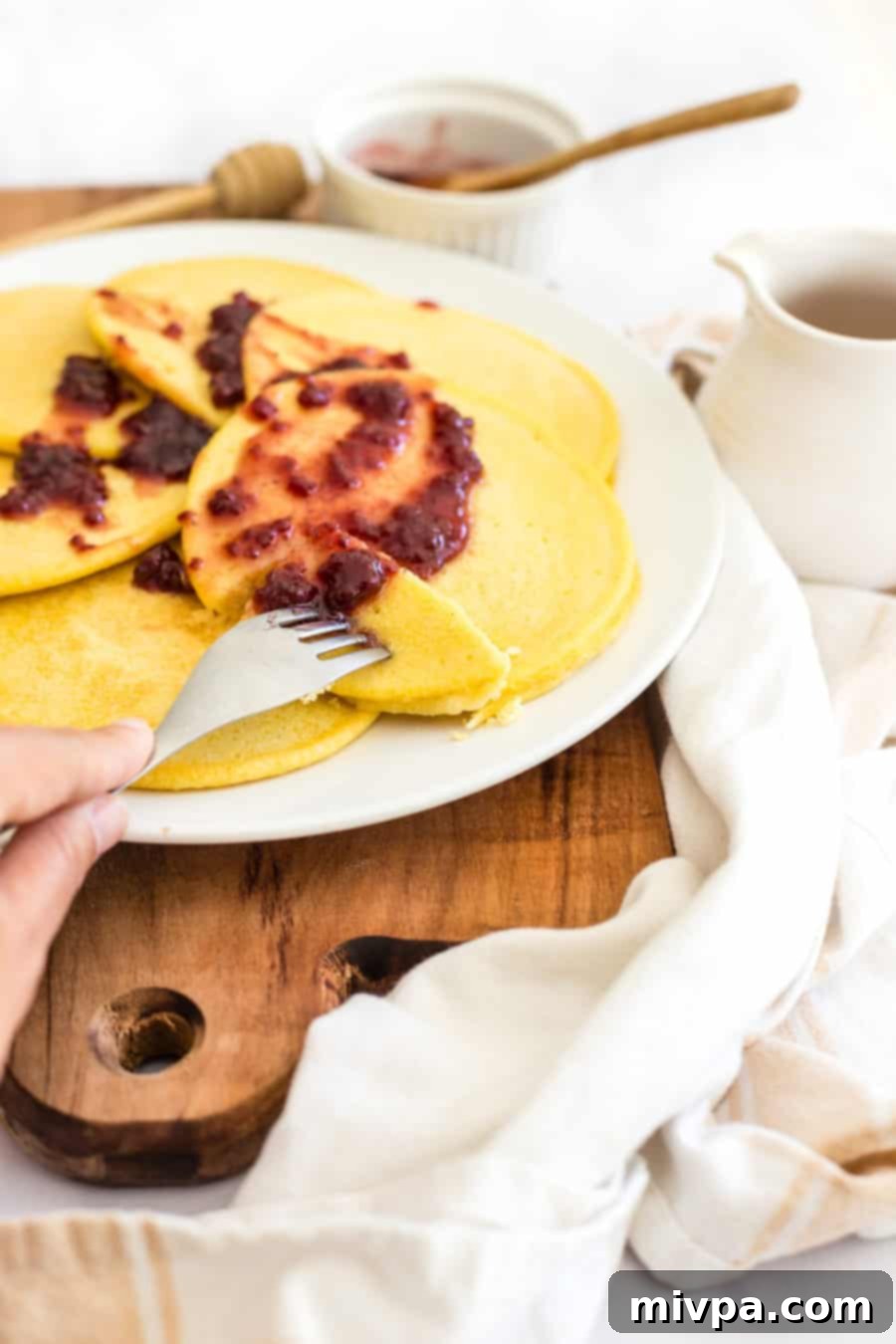A close-up shot of a stack of golden corn flour pancakes, highlighting their texture.