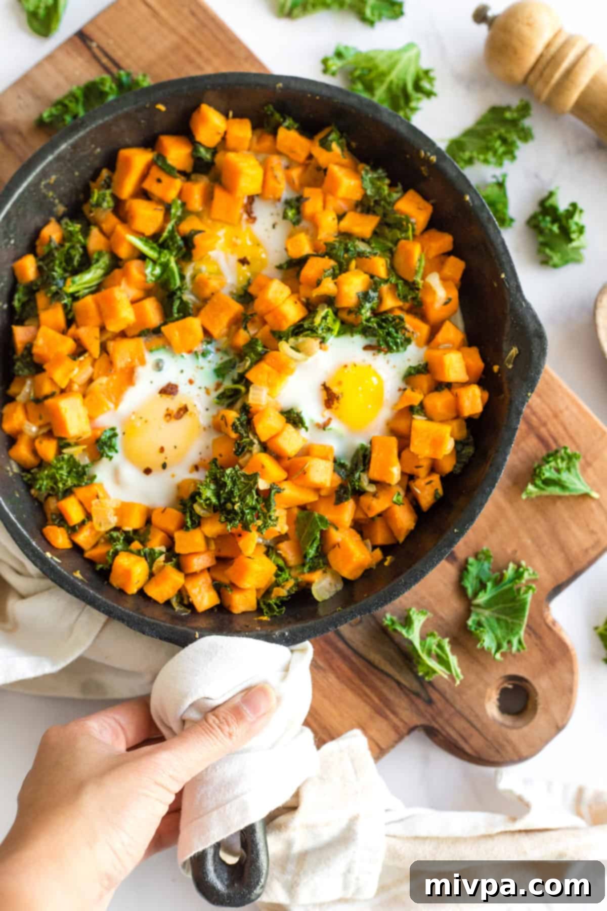 Close-up of cubed sweet potatoes, chopped onions, and fresh kale, ready for the breakfast skillet.
