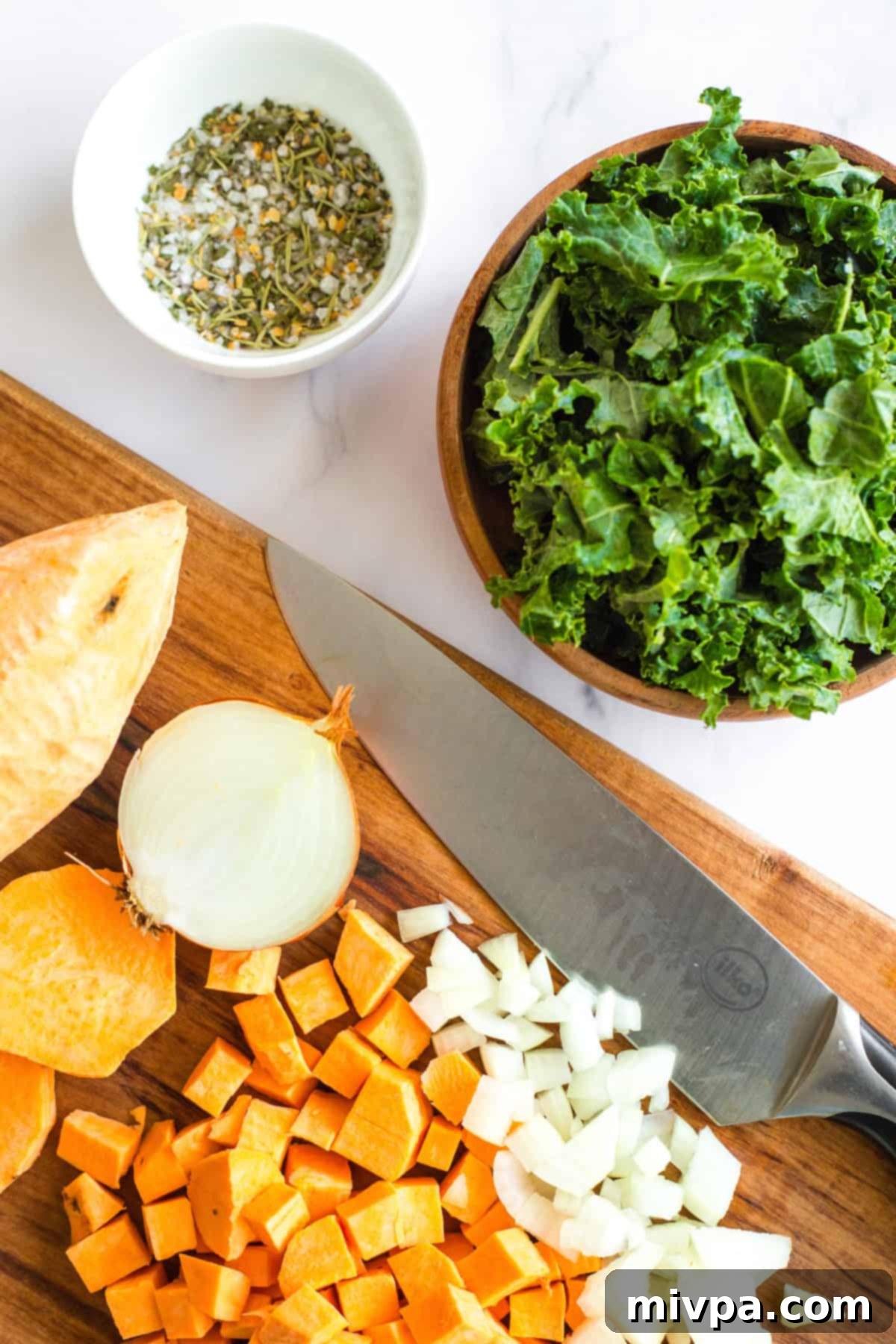 Variety of fresh vegetables, including sweet potatoes and kale, neatly arranged.