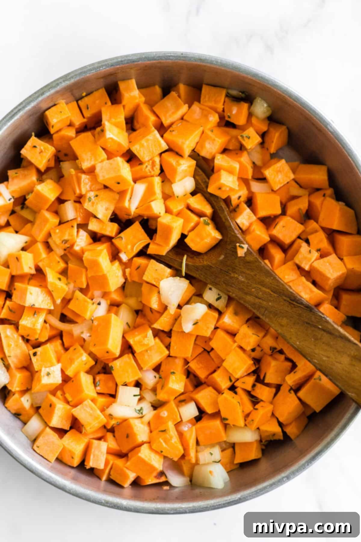 Sweet potatoes and onions sizzling in a cast-iron skillet, ready for cooking.