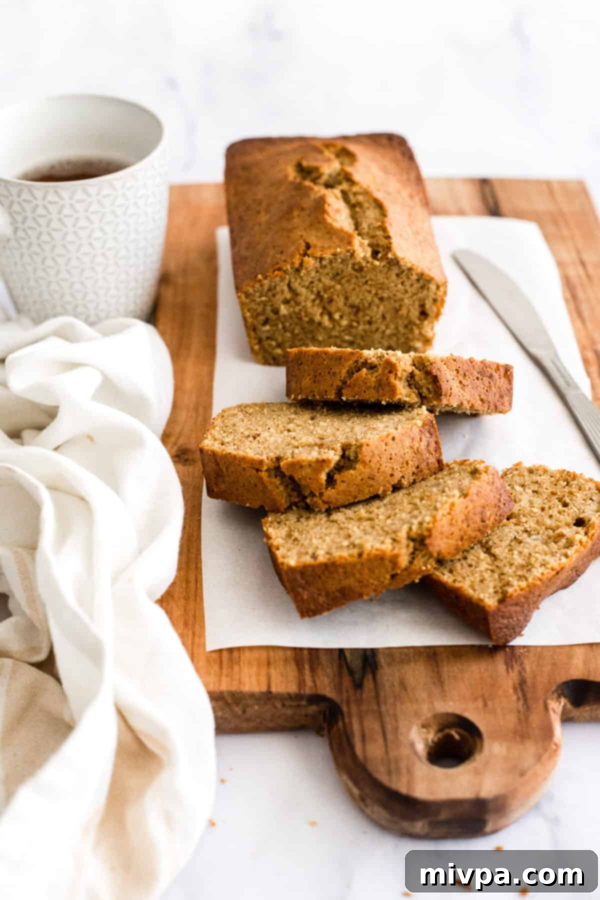 Sliced banana bread on parchment-lined wooden board.