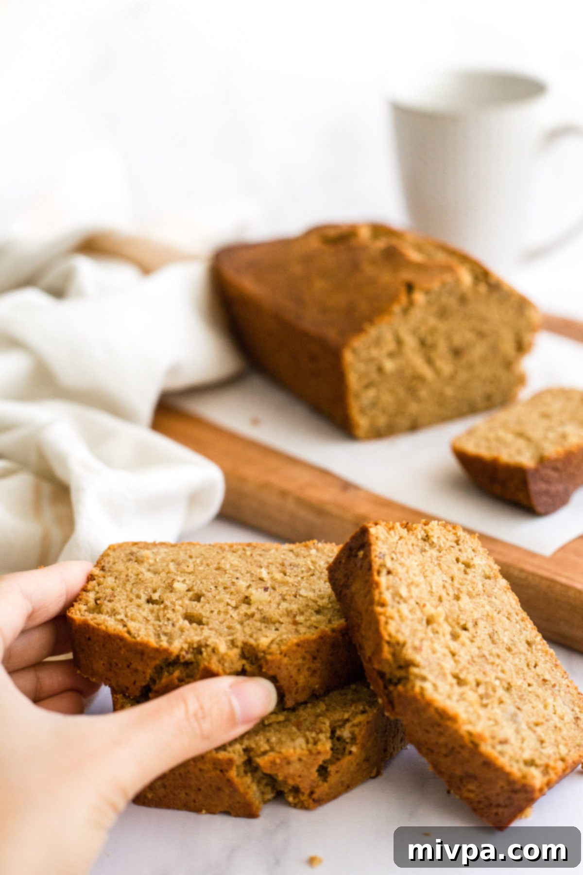 Hand reaching for a slice of banana bread.