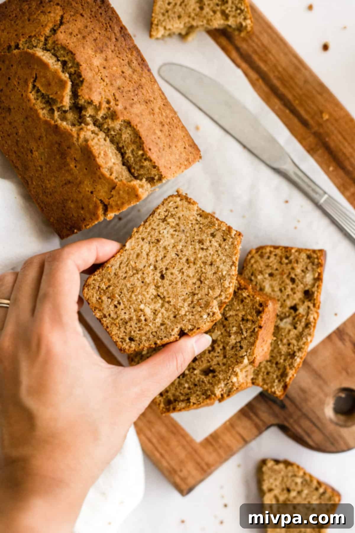 Hand holding a slice of gluten-free banana bread.