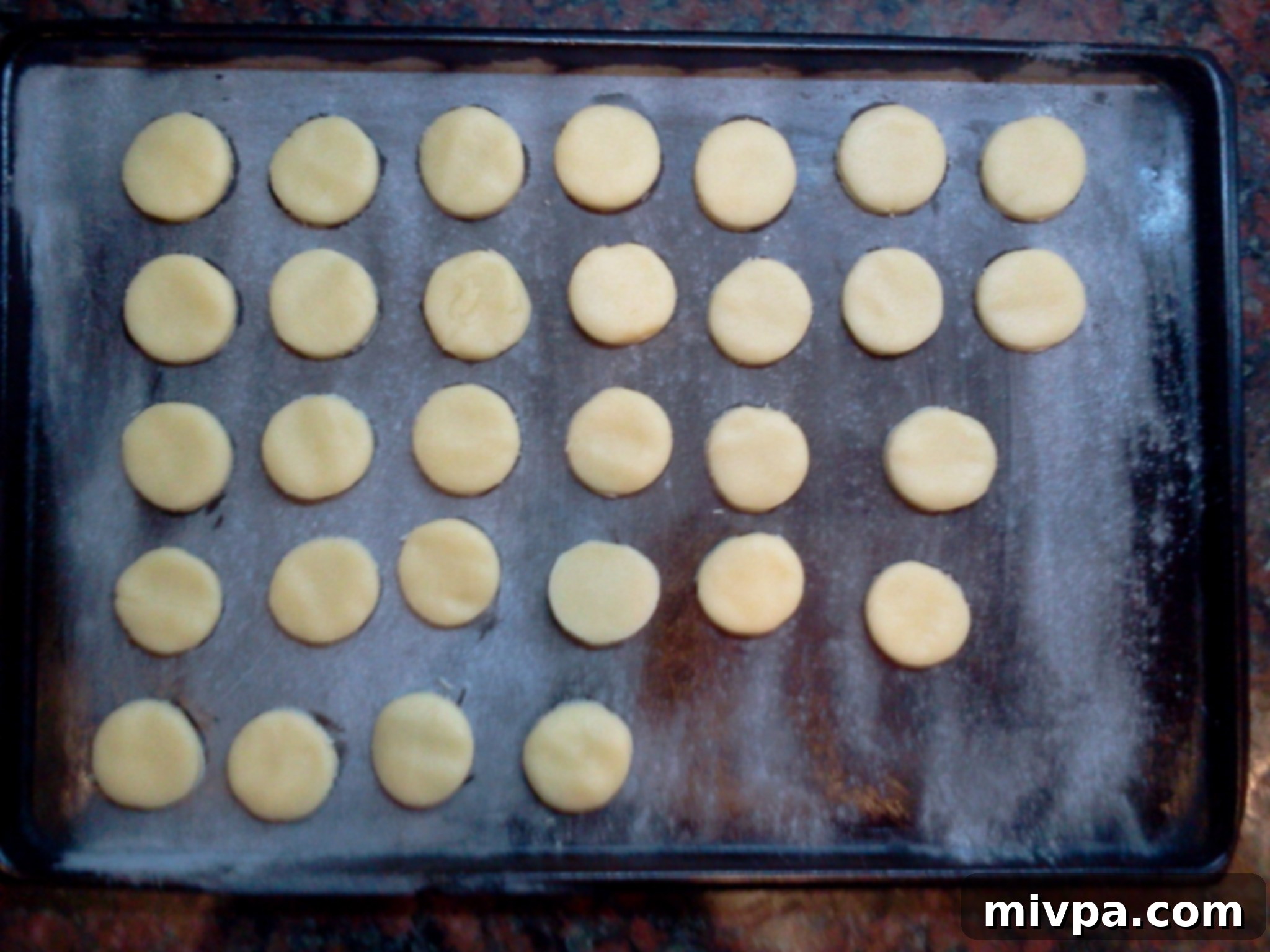 Another perspective of the spaced-out round cookie dough pieces on a baking sheet, ready for their transformation in the oven.