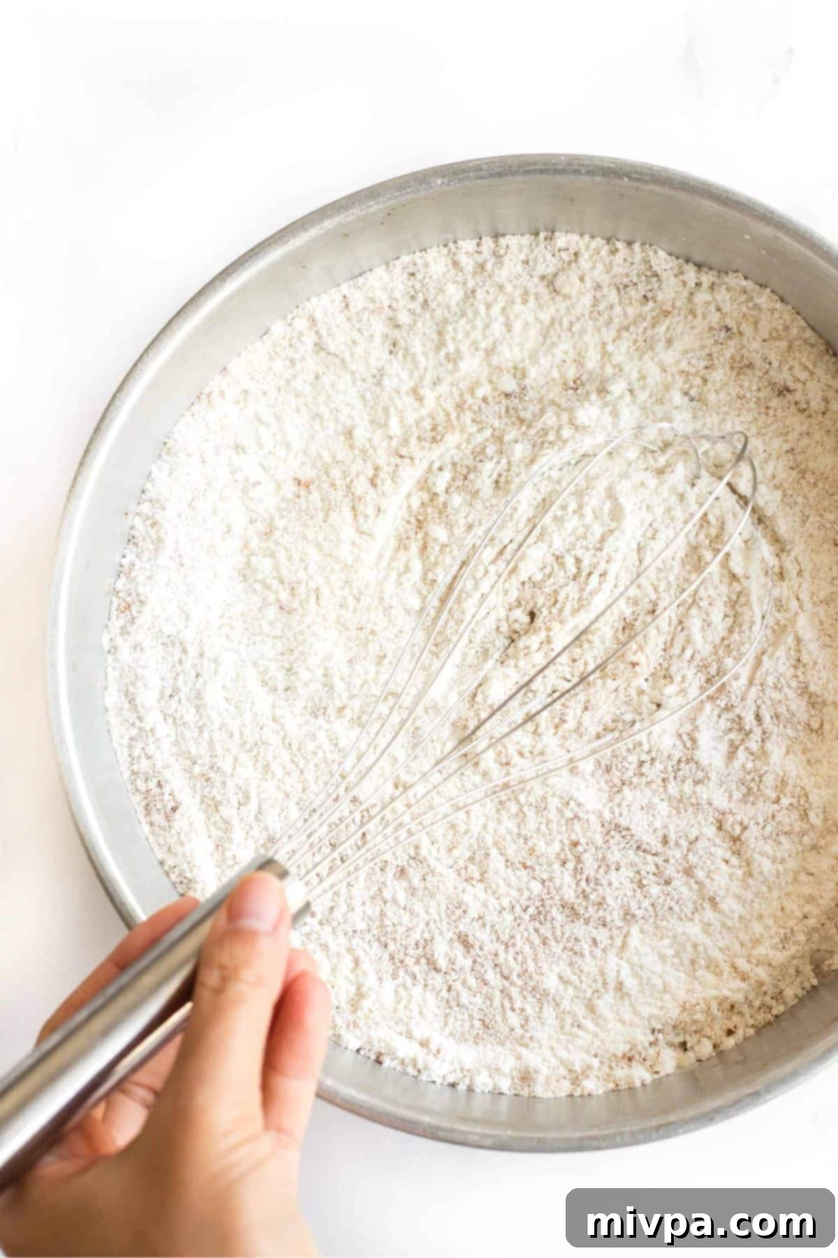 Whisking dry ingredients in metal bowl.