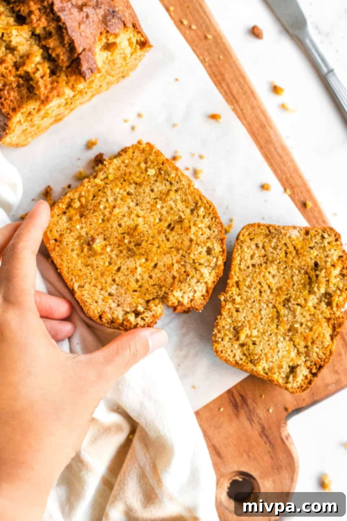Hand reaching for a slice of carrot cake bread.