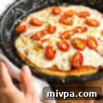 Hand reaching for a pizza in baking tray