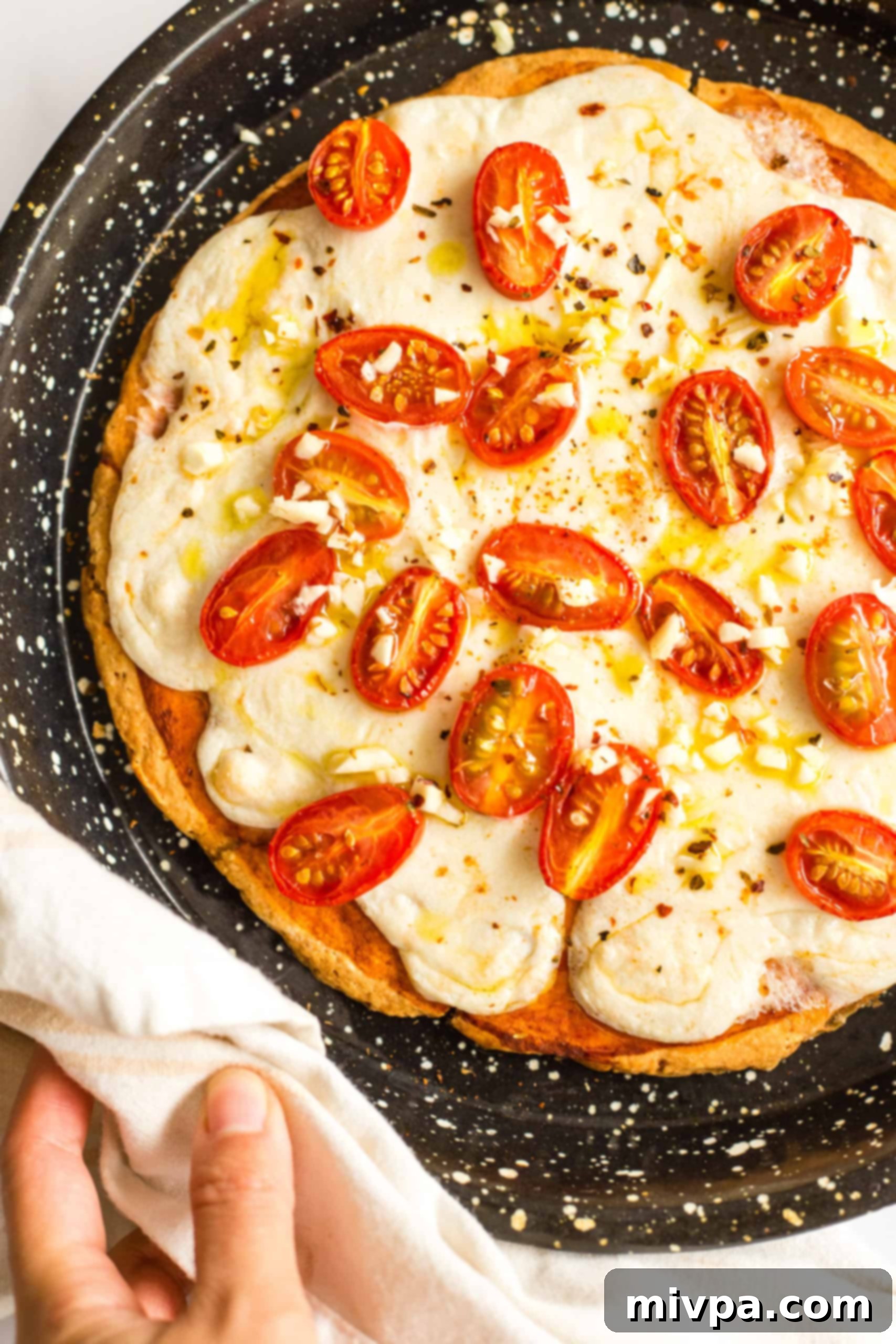 Hand holding a gluten-free pizza in a pizza pan.