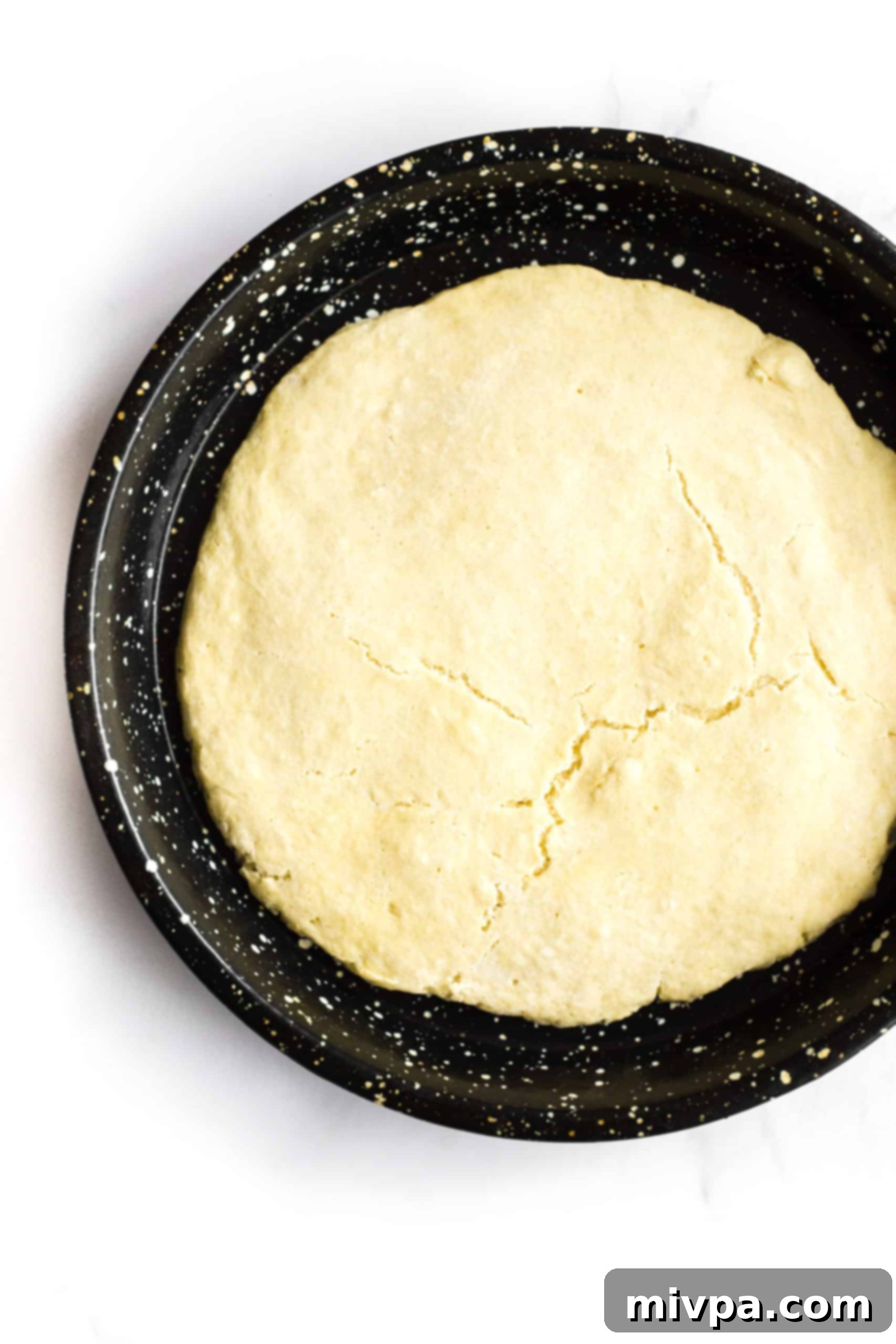 Gluten-free pizza crust in a pizza pan.