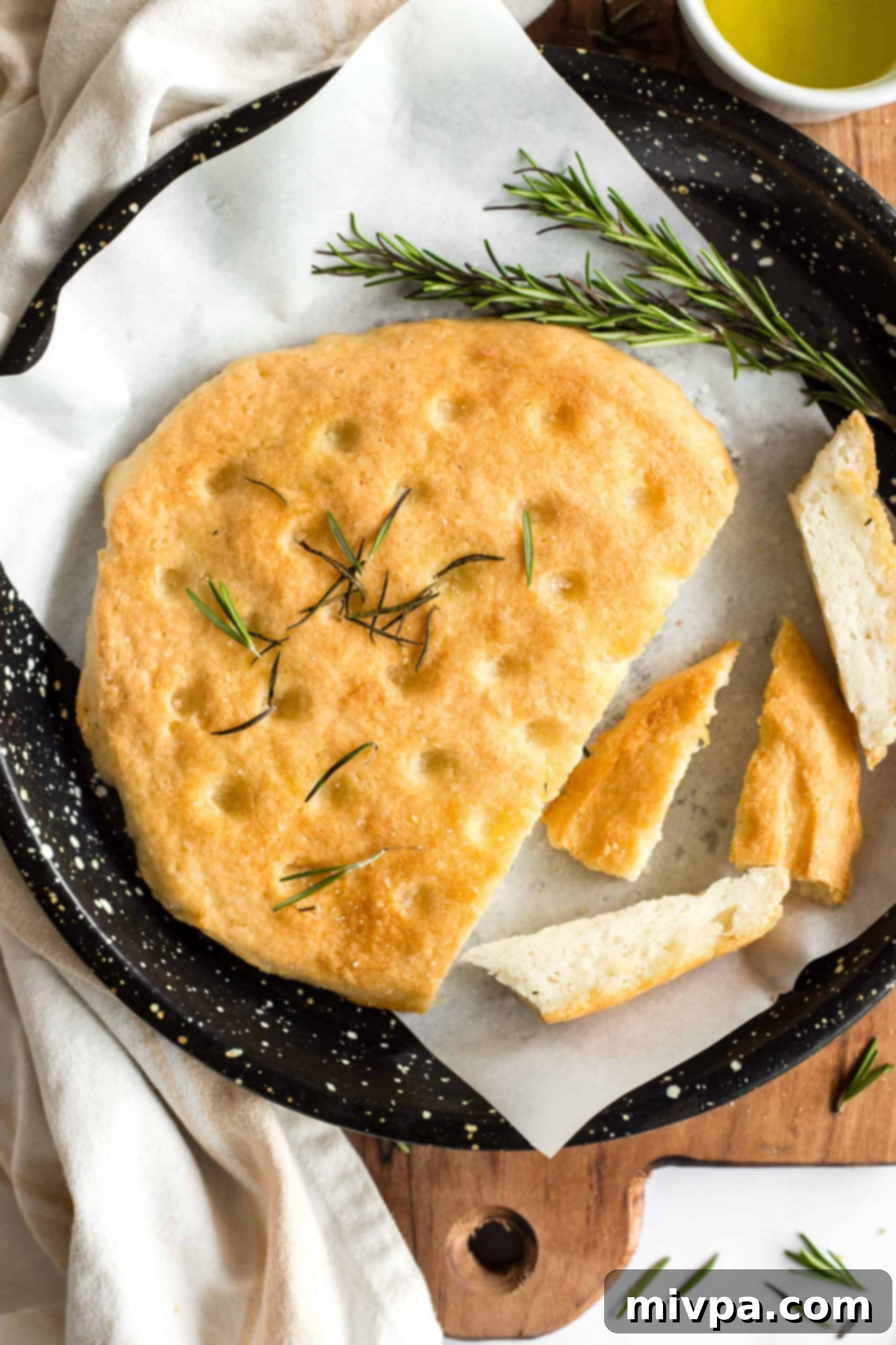 The Best Gluten-Free Focaccia Bread (Dairy-Free, Vegan) Sliced gluten-free focaccia bread on a parchment-lined baking sheet.