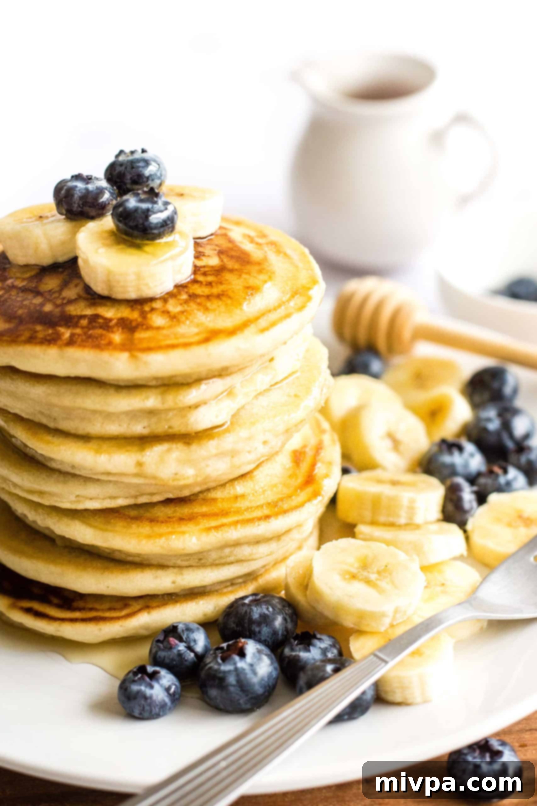 Fluffy Gluten-Free Pancakes (Dairy-Free) A stack of gluten-free pancakes topped with blueberries and sliced bananas on a plate, ready to be served.
