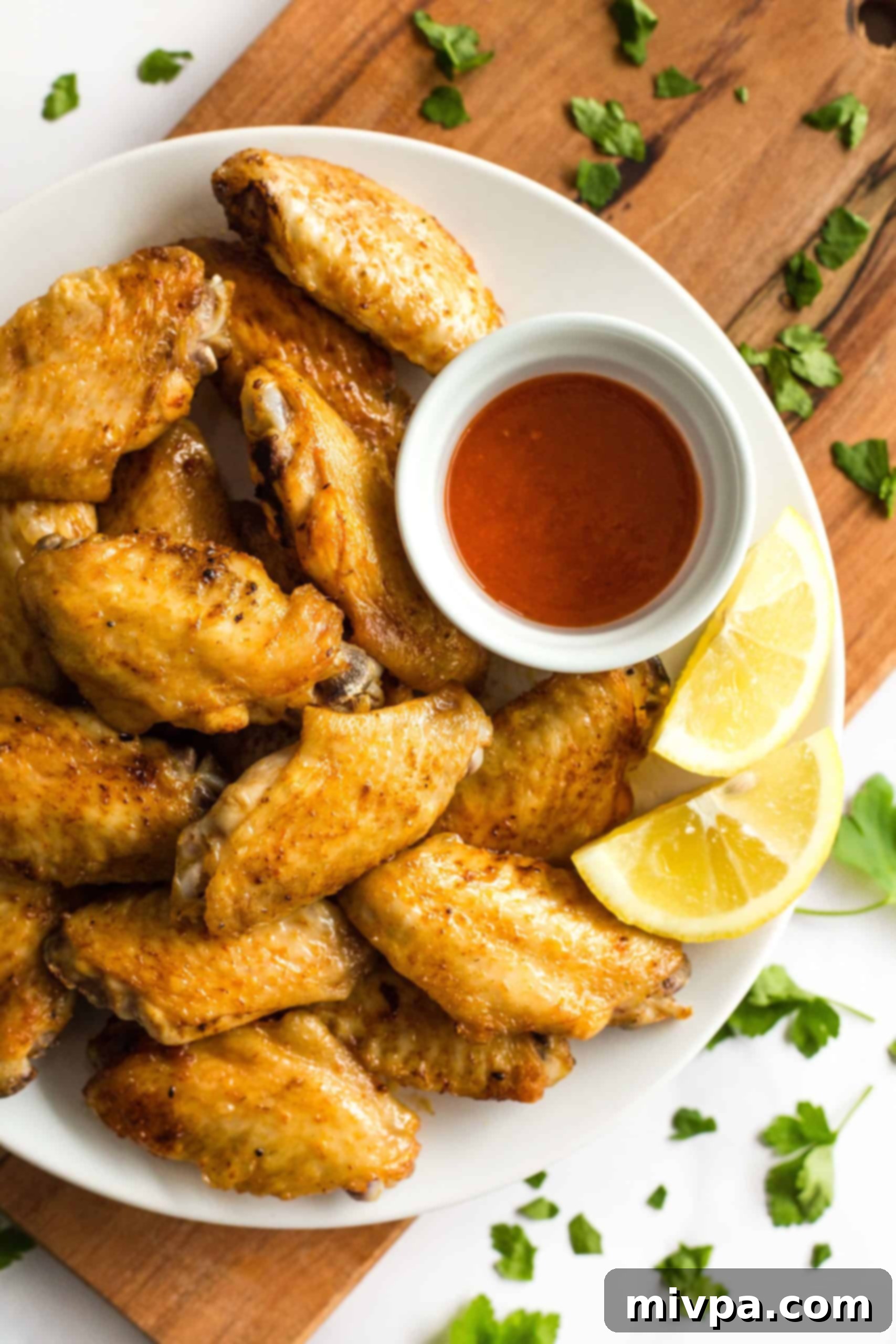 A plate of crispy air fryer chicken wings with sriracha chili sauce.