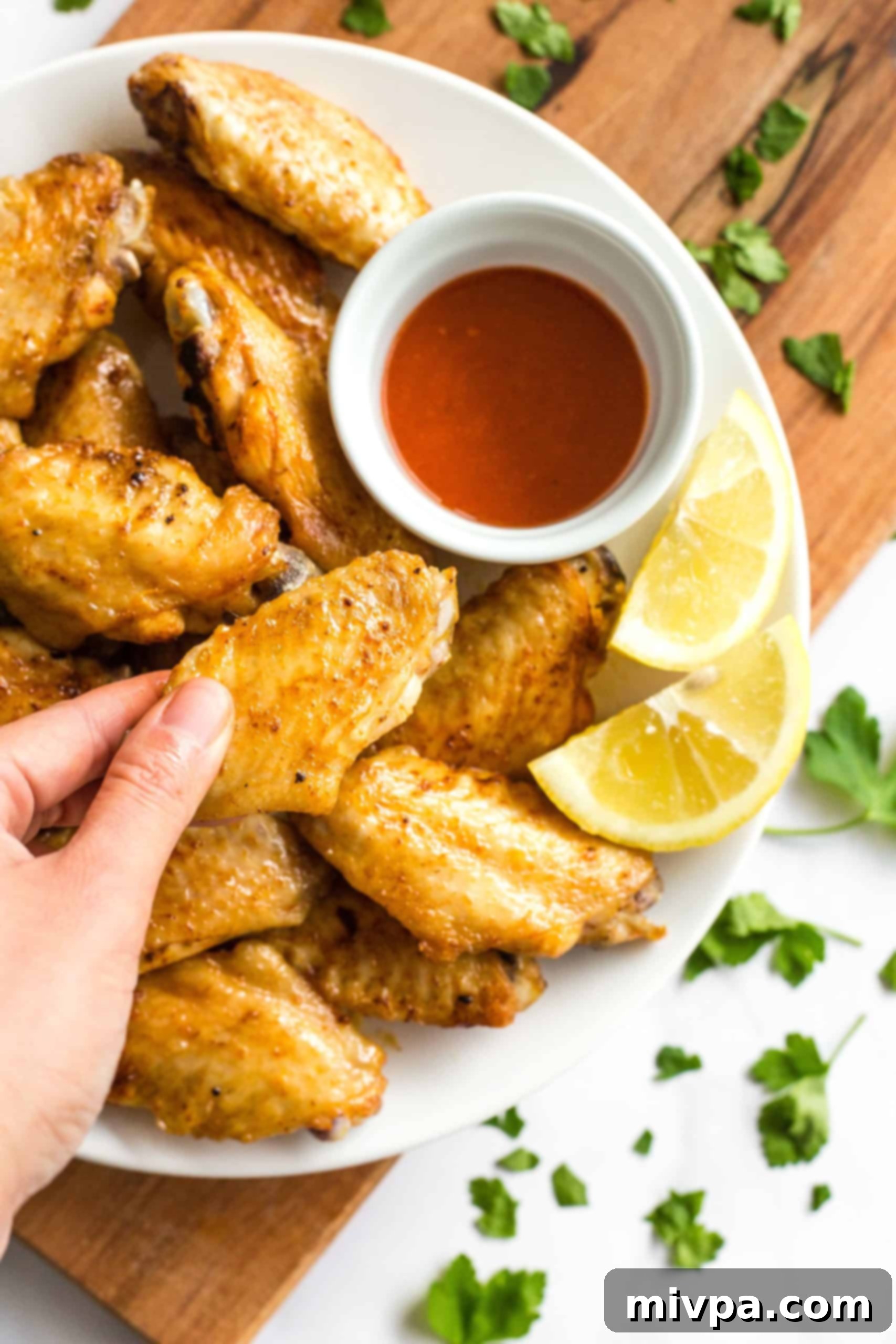 Hand holding up a crispy chicken wing.