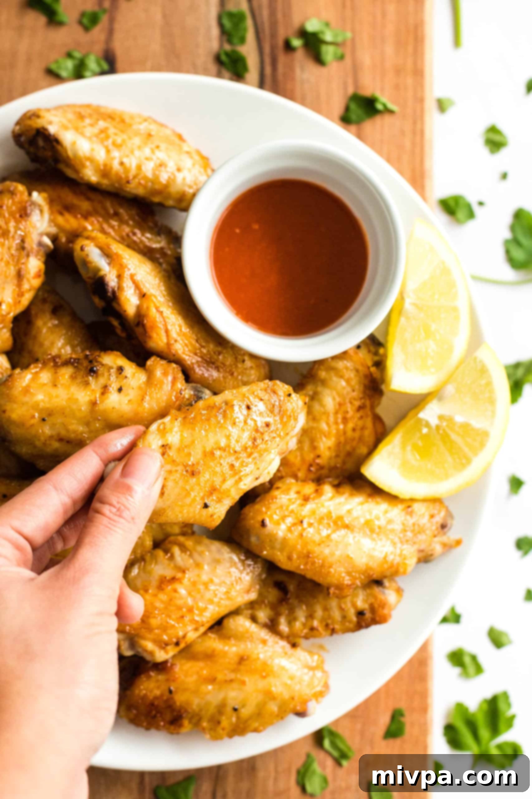 A hand holding up a crispy air fryer chicken wing. 
