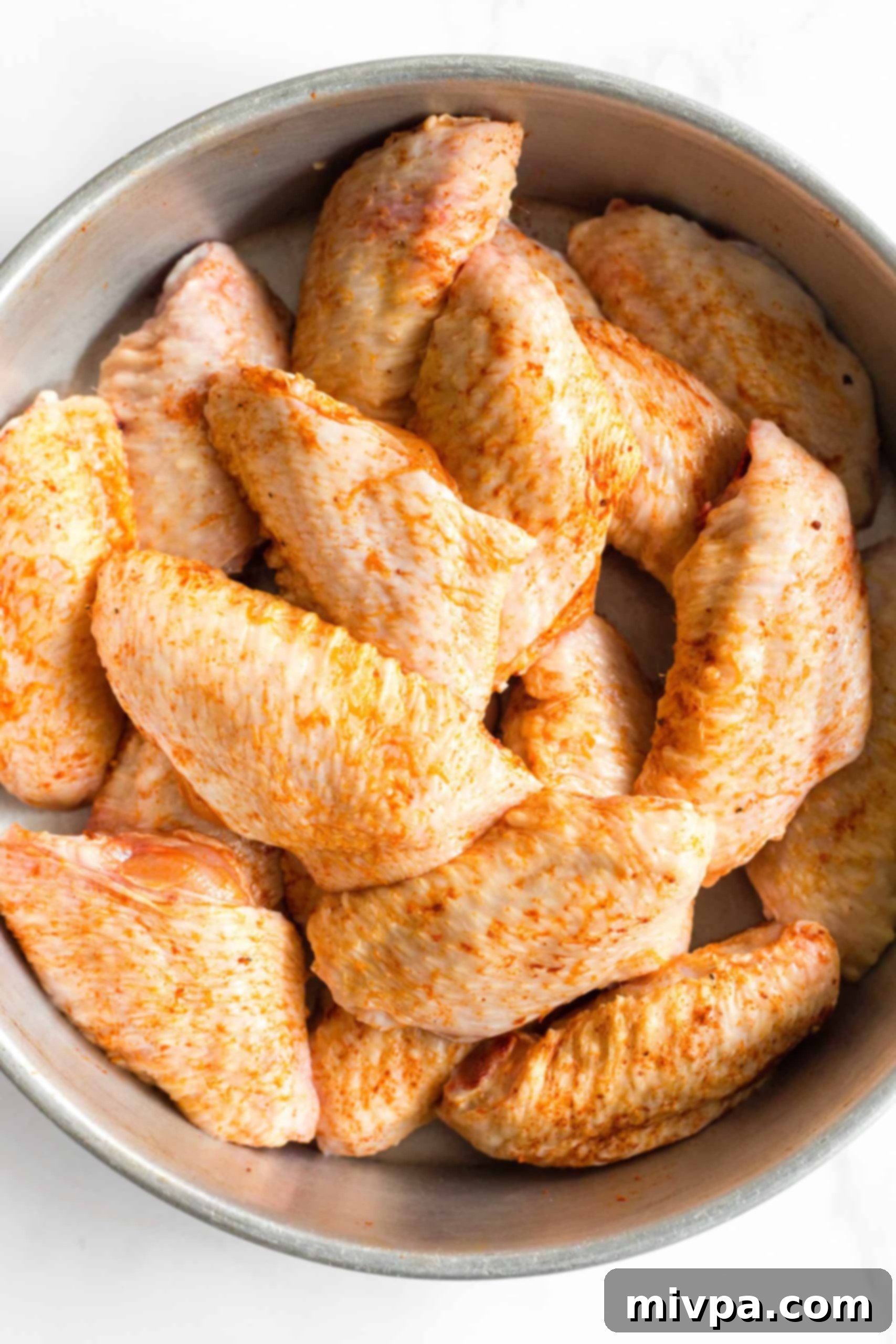 Seasoned uncooked chicken wings ready to be cooked in the air fryer.