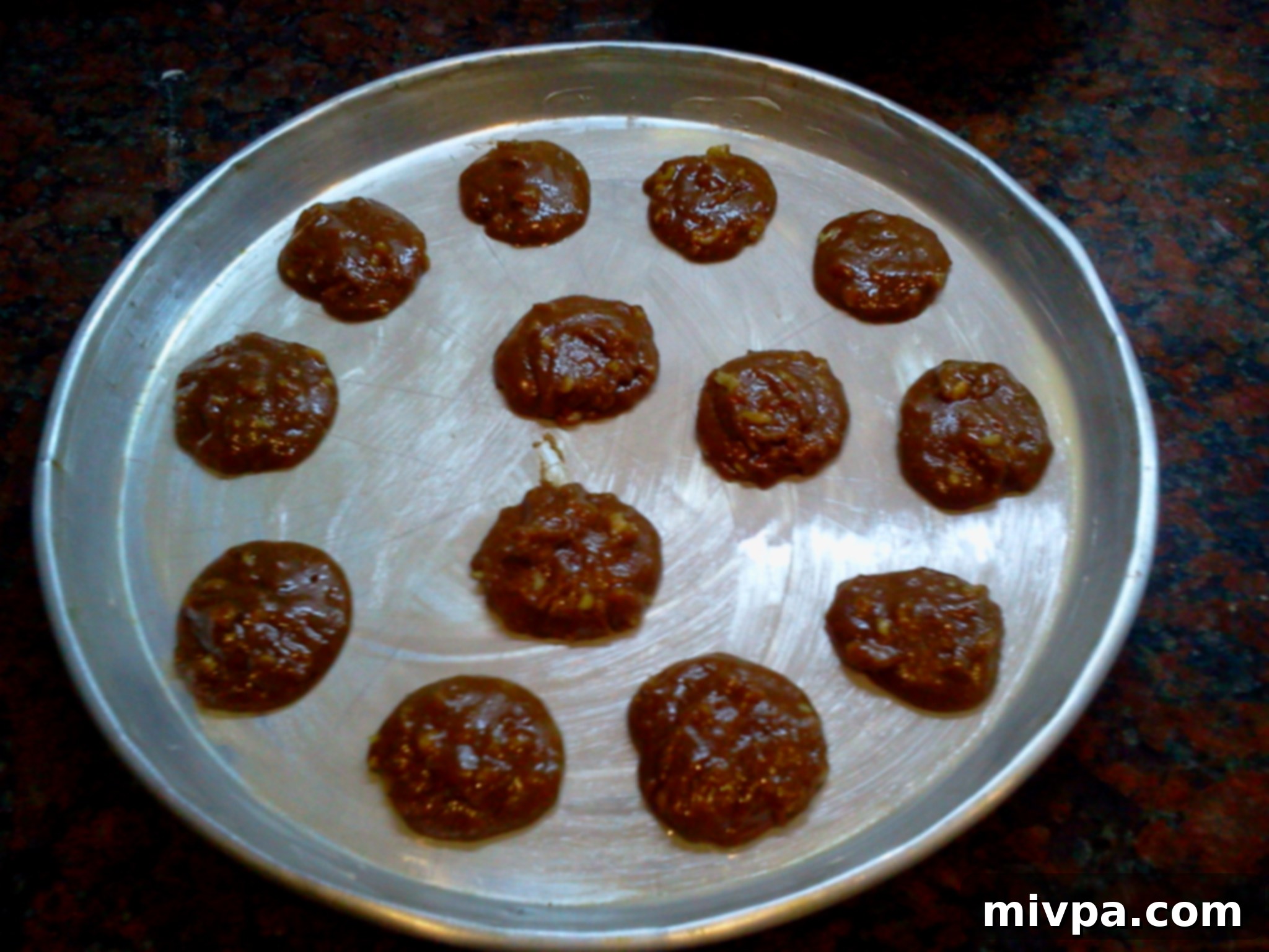 Small dollops of coffee walnut cookie dough neatly arranged on a greased baking tray.