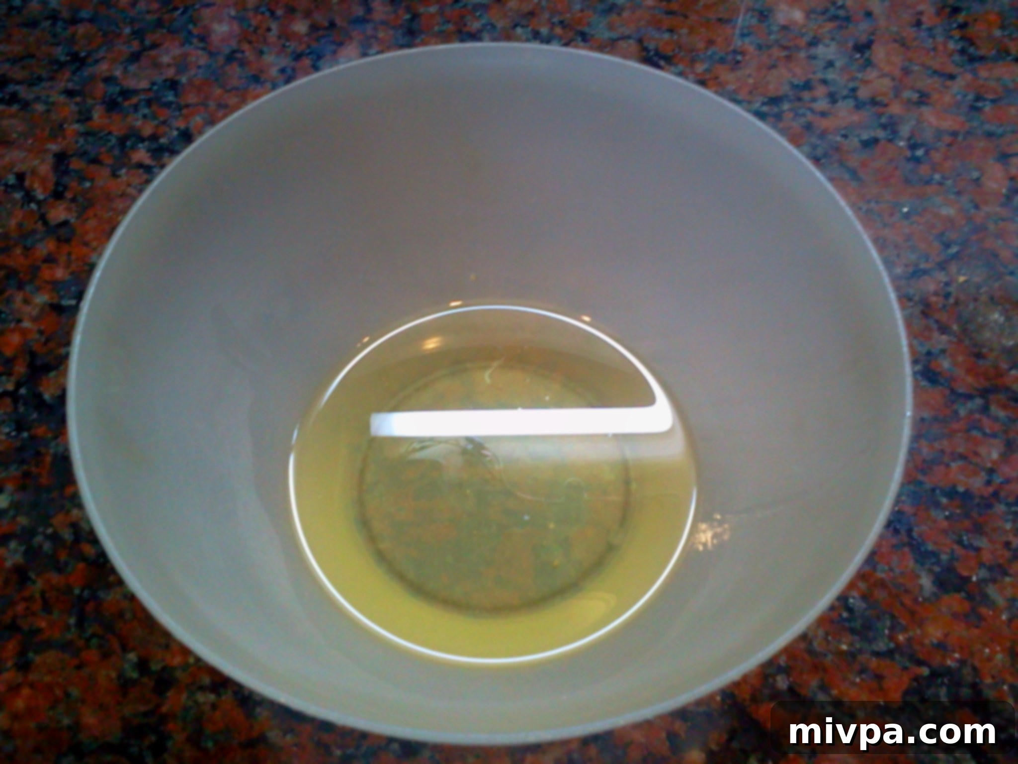 A measuring cup filled with clear vegetable oil, an essential liquid ingredient.
