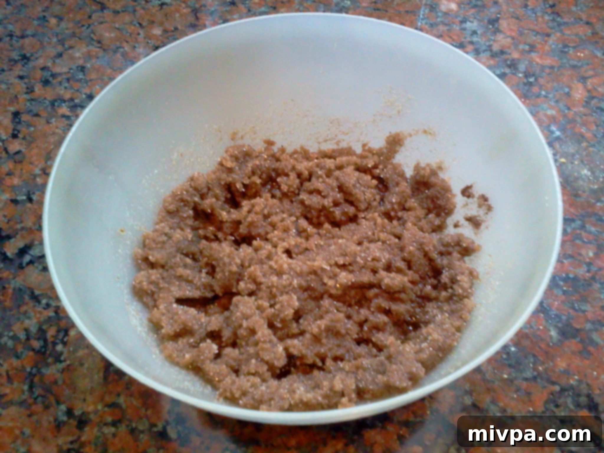 A close-up of the creamed mixture of oil, sugar, and coffee powder, showing a smooth texture.