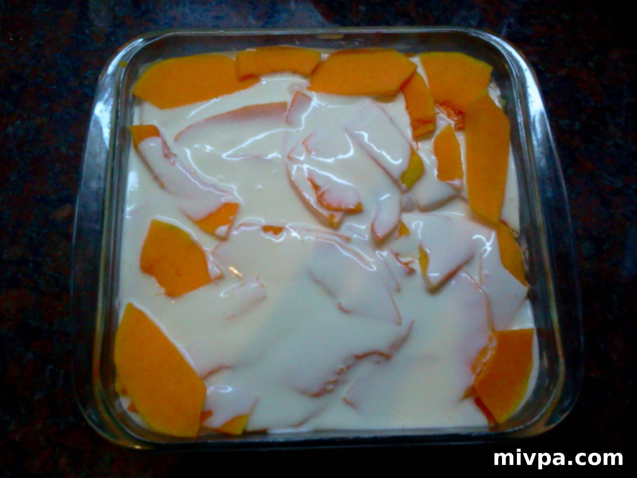 Pouring the remaining milk cream over the second layer of butternut squash in the baking dish