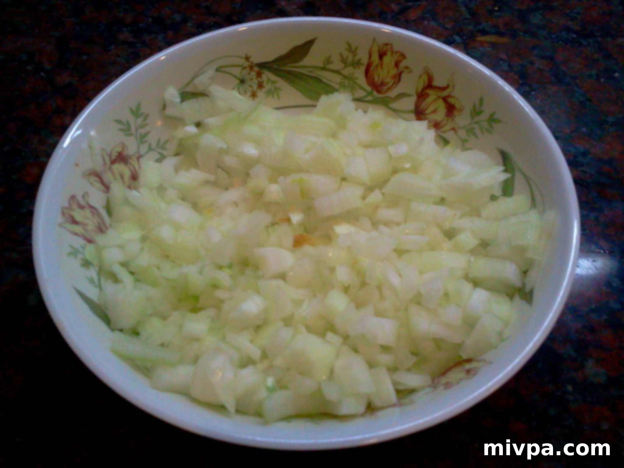 Finely chopped white onions in a bowl, prepared for the next step of the Butternut Squash Tower recipe
