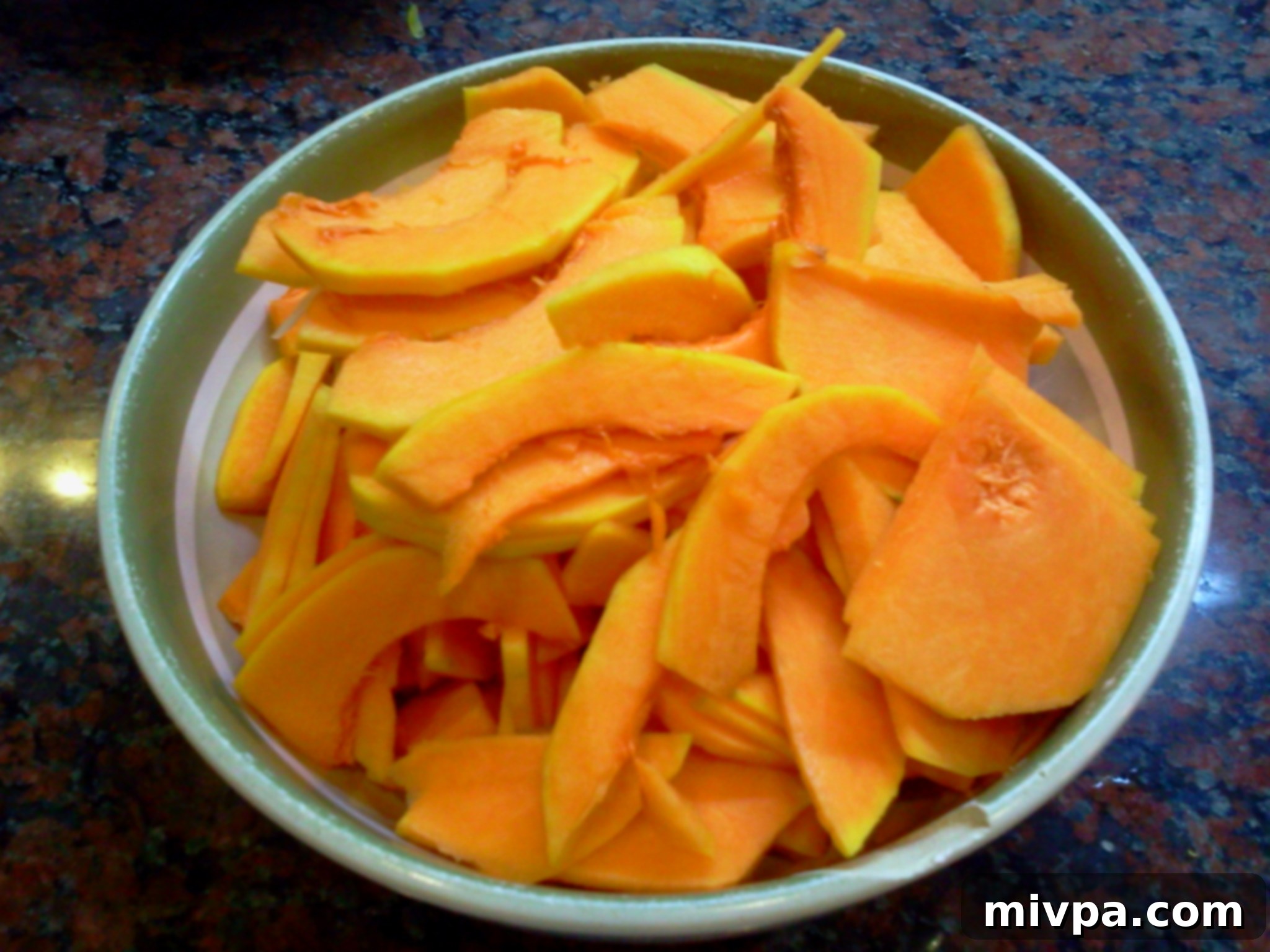 Butternut squash being sliced thinly and evenly, ideal for layering in the tower