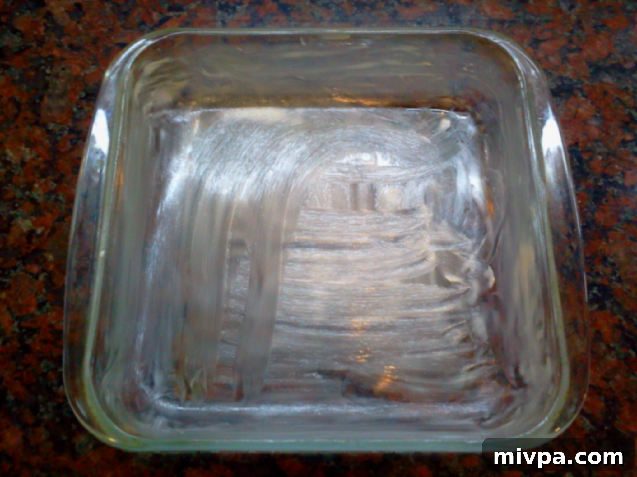 A glass oven-safe baking mould being greased with butter, preparing for the butternut squash layers