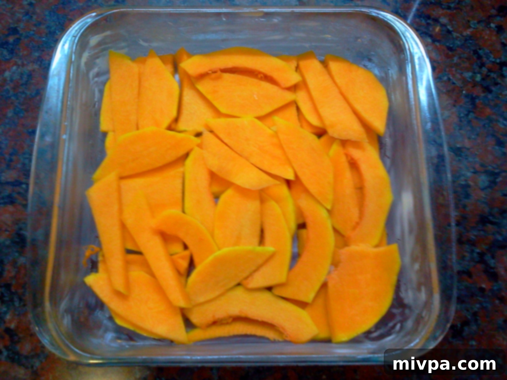 First layer of thinly sliced butternut squash neatly arranged in the bottom of the baking mould