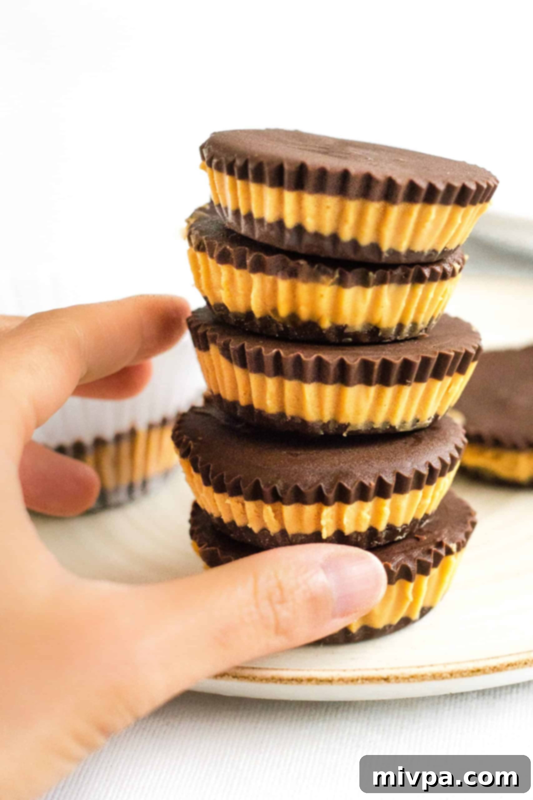 Healthy Peanut Butter Cups (Gluten-Free, Vegan) Hand reaching for a stack of healthy peanut butter cups.