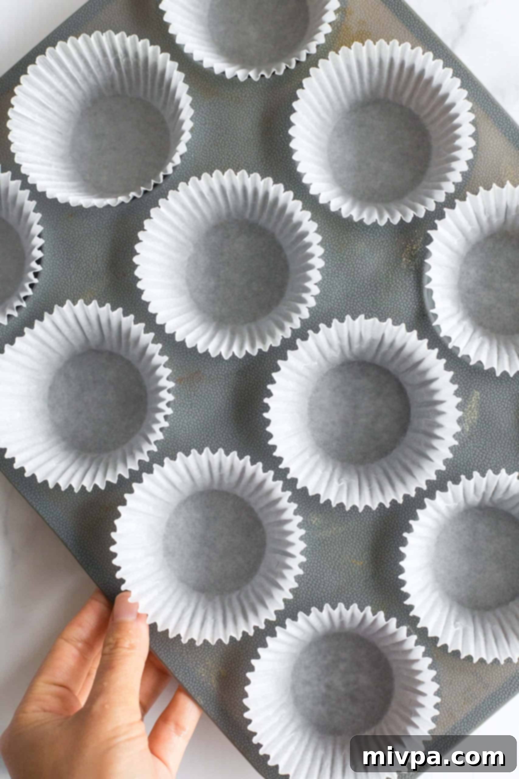 Healthy Peanut Butter Cups (Gluten-Free, Vegan) Hand holding silicon muffin mold lined with paper liners.