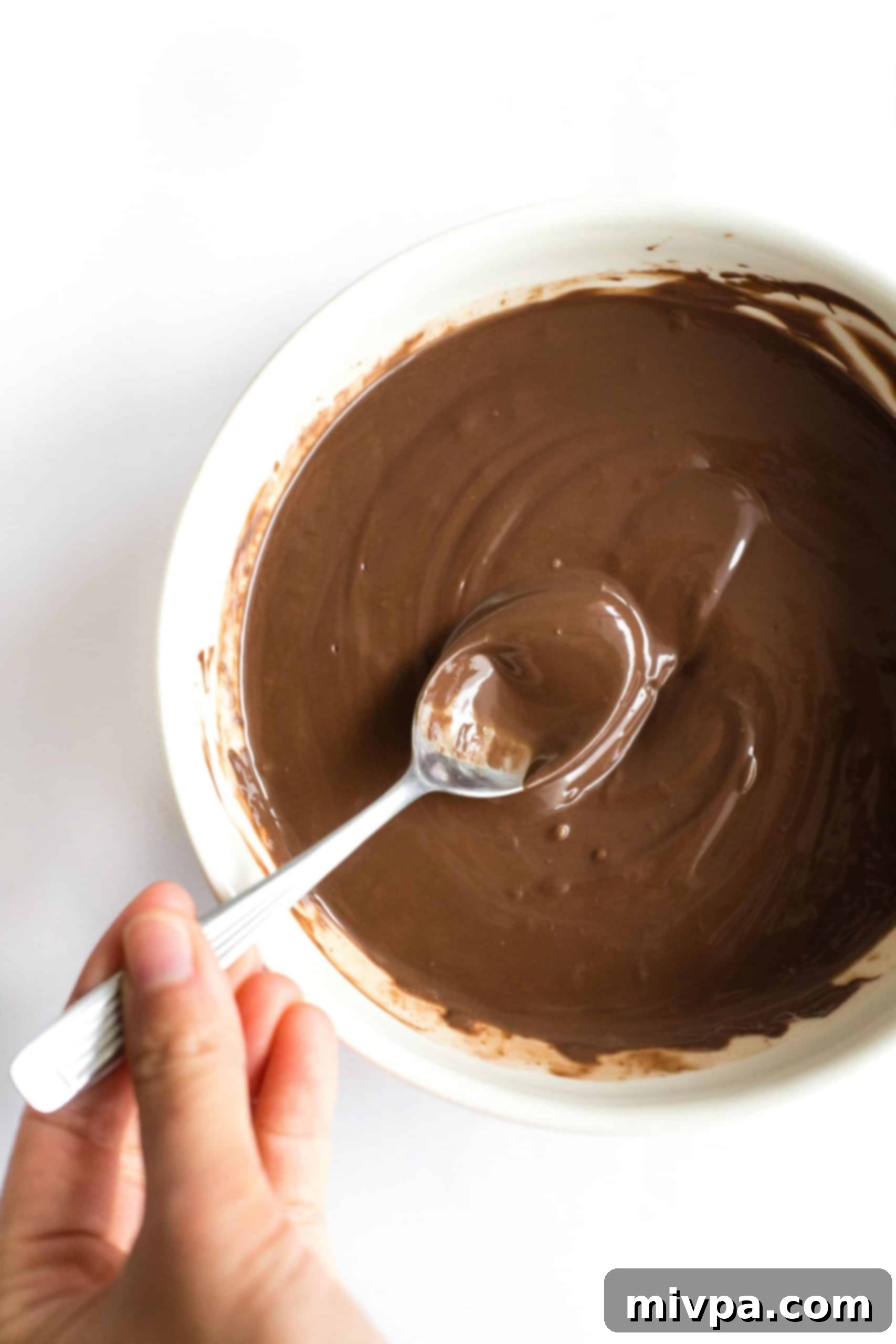 Healthy Peanut Butter Cups (Gluten-Free, Vegan) Mixing a bowl of melted chocolate with a metal spoon.