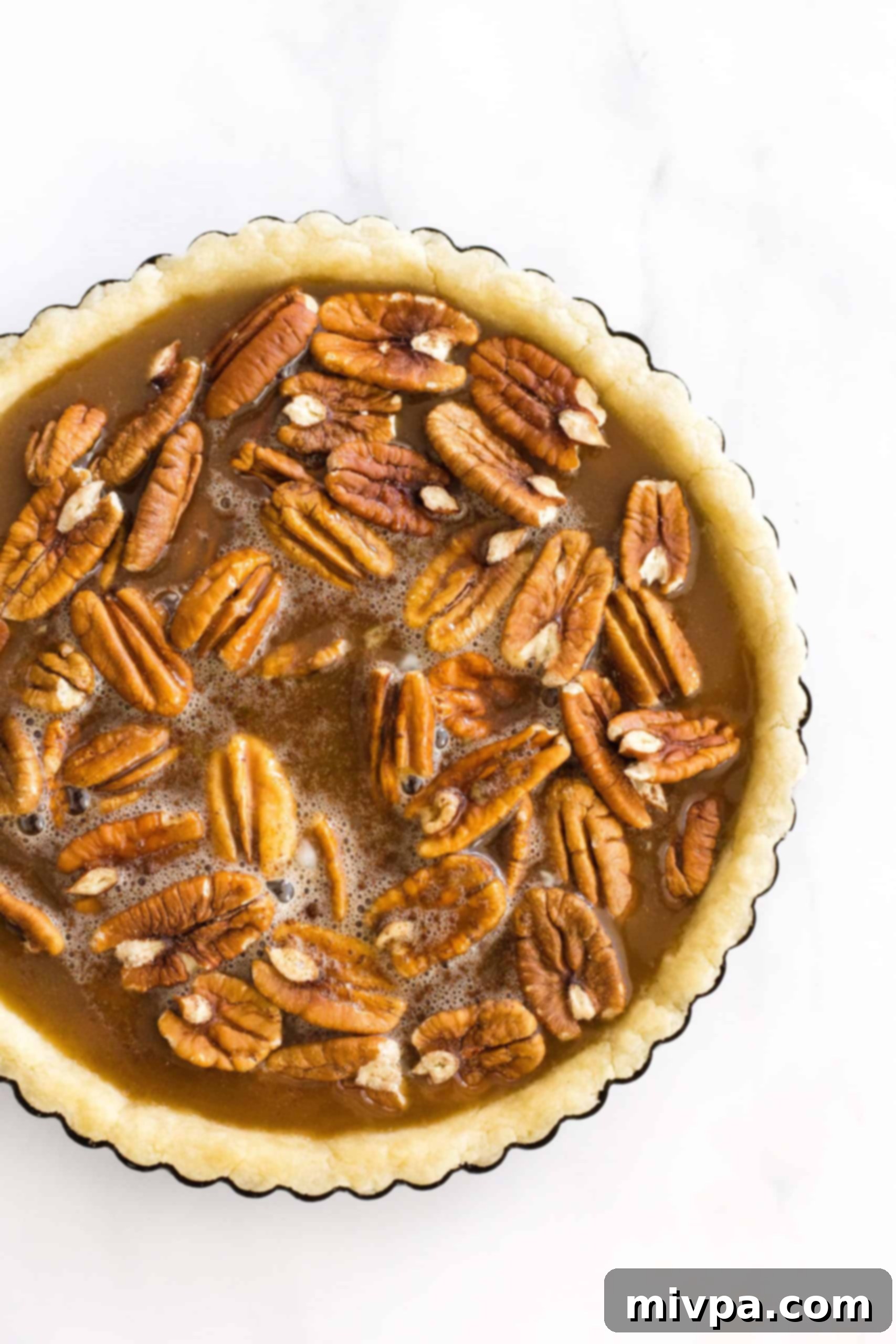Easy Gluten-Free Pecan Pie Recipe (Dairy-Free) Uncooked pecan pie in a pie tin ready to be baked.