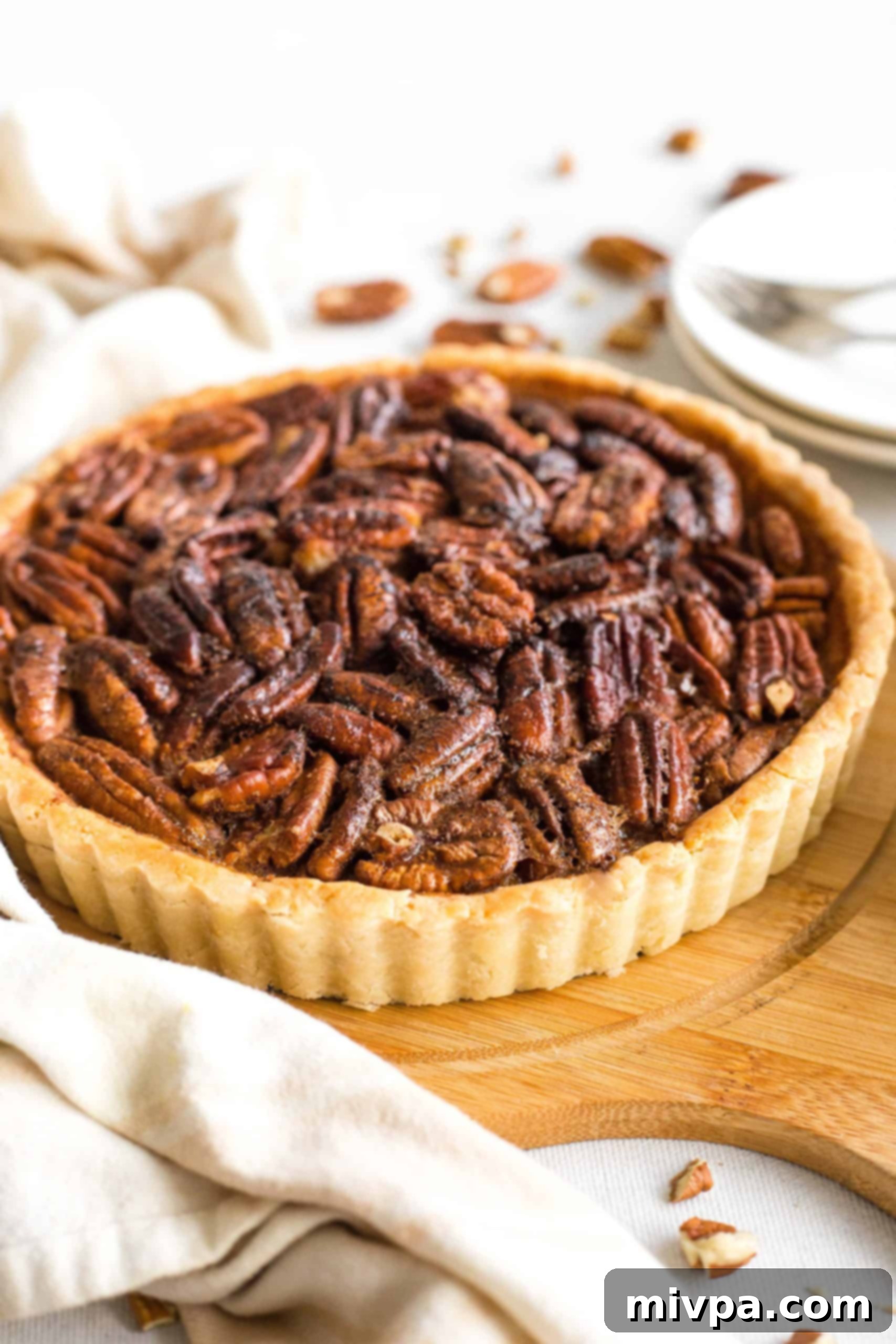 Easy Gluten-Free Pecan Pie Recipe (Dairy-Free) Whole pecan pie on a wooden board.