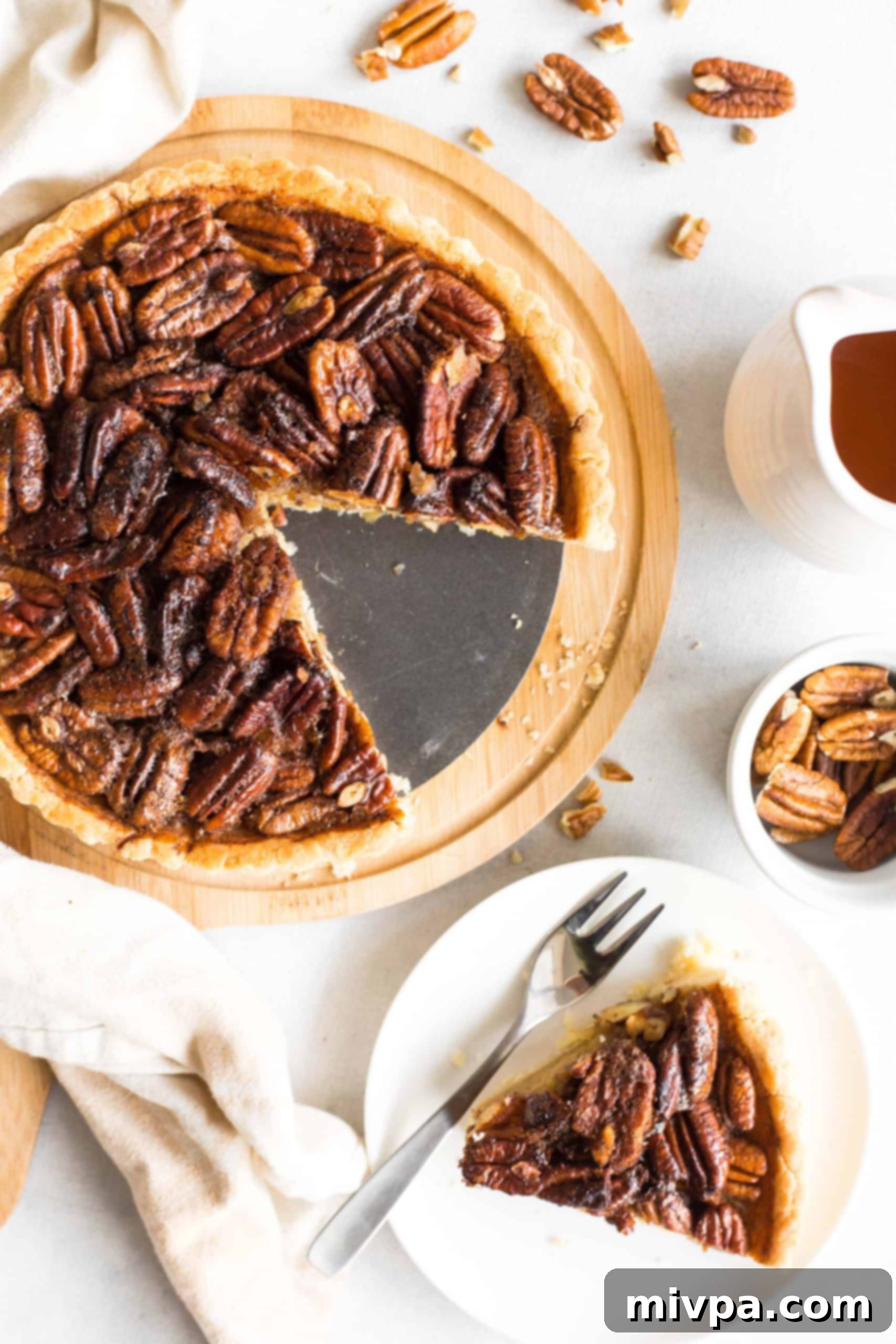Easy Gluten-Free Pecan Pie Recipe (Dairy-Free) Whole pecan pie and a slice of pie on a white plate.