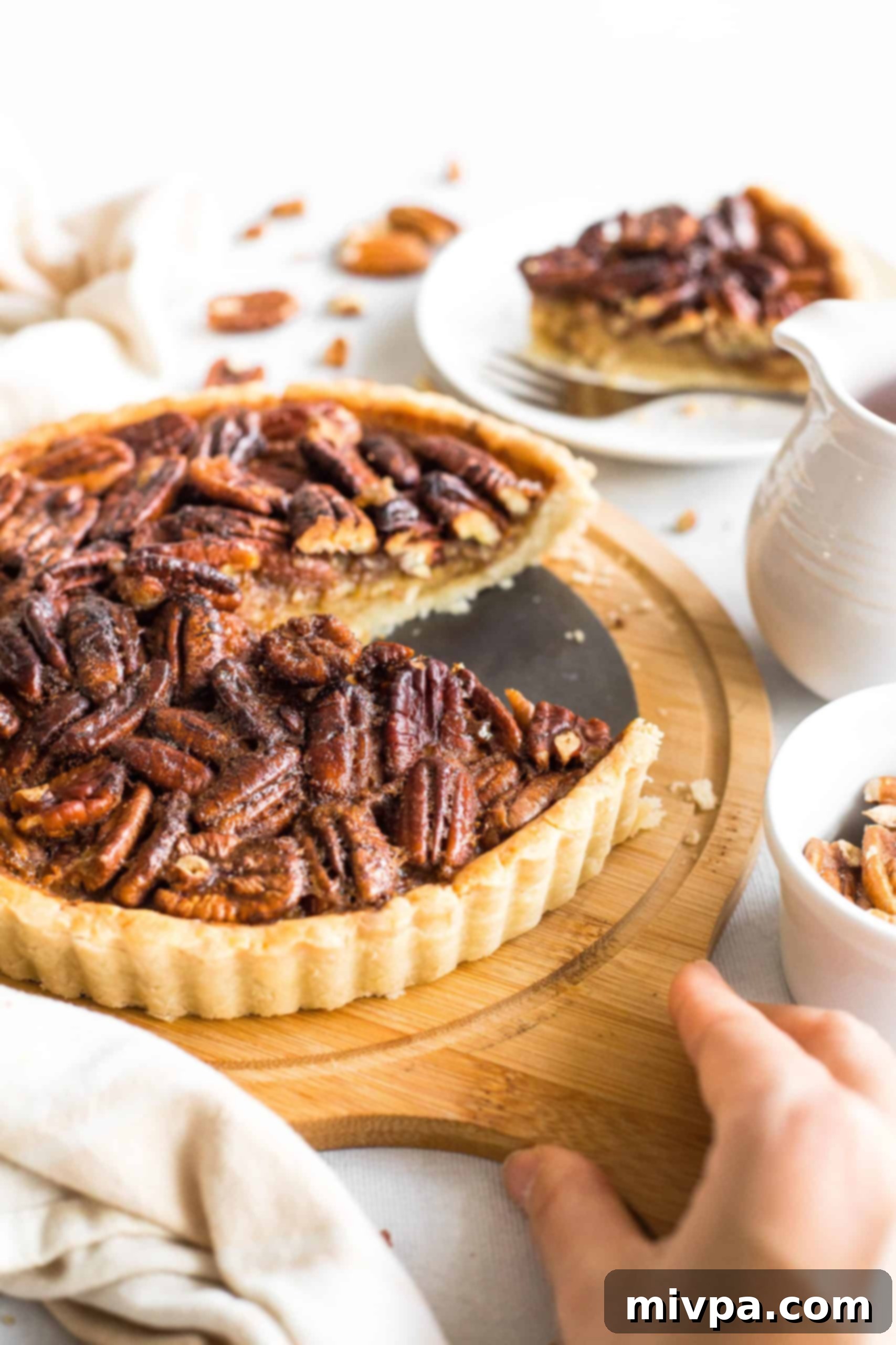 Easy Gluten-Free Pecan Pie Recipe (Dairy-Free) Hand holding a wooden board with gluten-free pecan pie on it.
