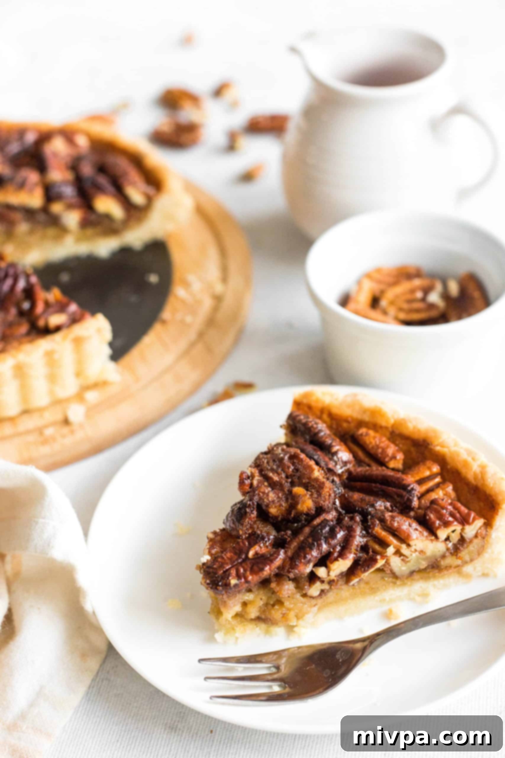 Easy Pecan Pie Recipe (Gluten-Free, Dairy-Free) A slice of dairy-free pecan pie on a white plate.