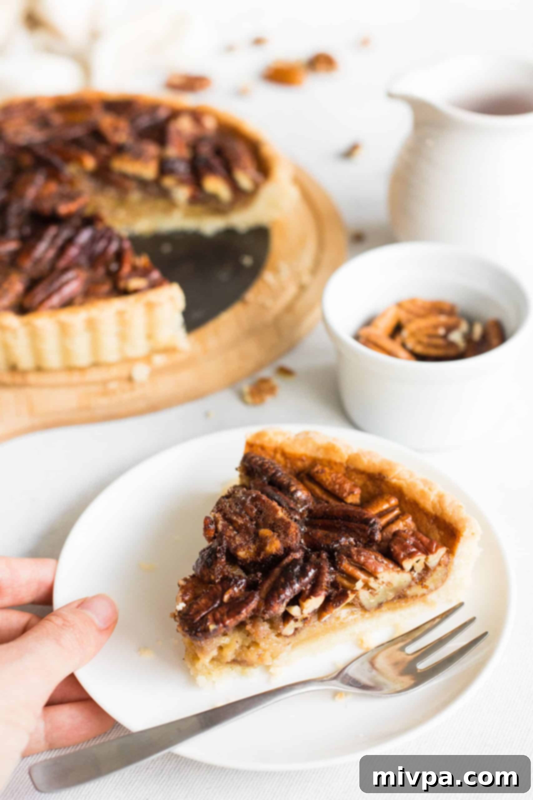 Gluten-Free Dairy-Free Pecan Pie Hand holding a plate with a slice of dairy-free pecan pie.
