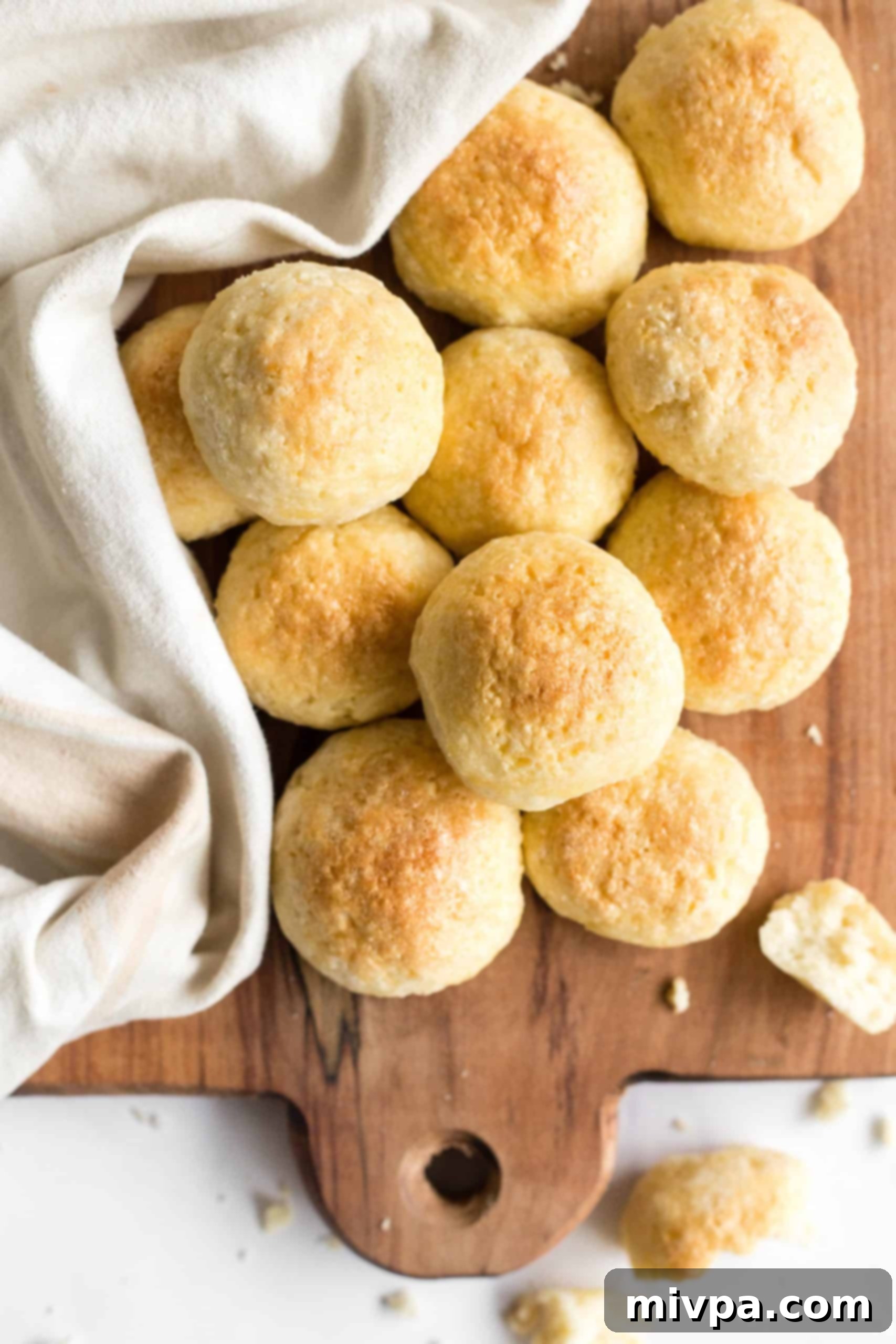 A top-down view of beautifully baked gluten-free yeast rolls arranged on a warm wooden board.
