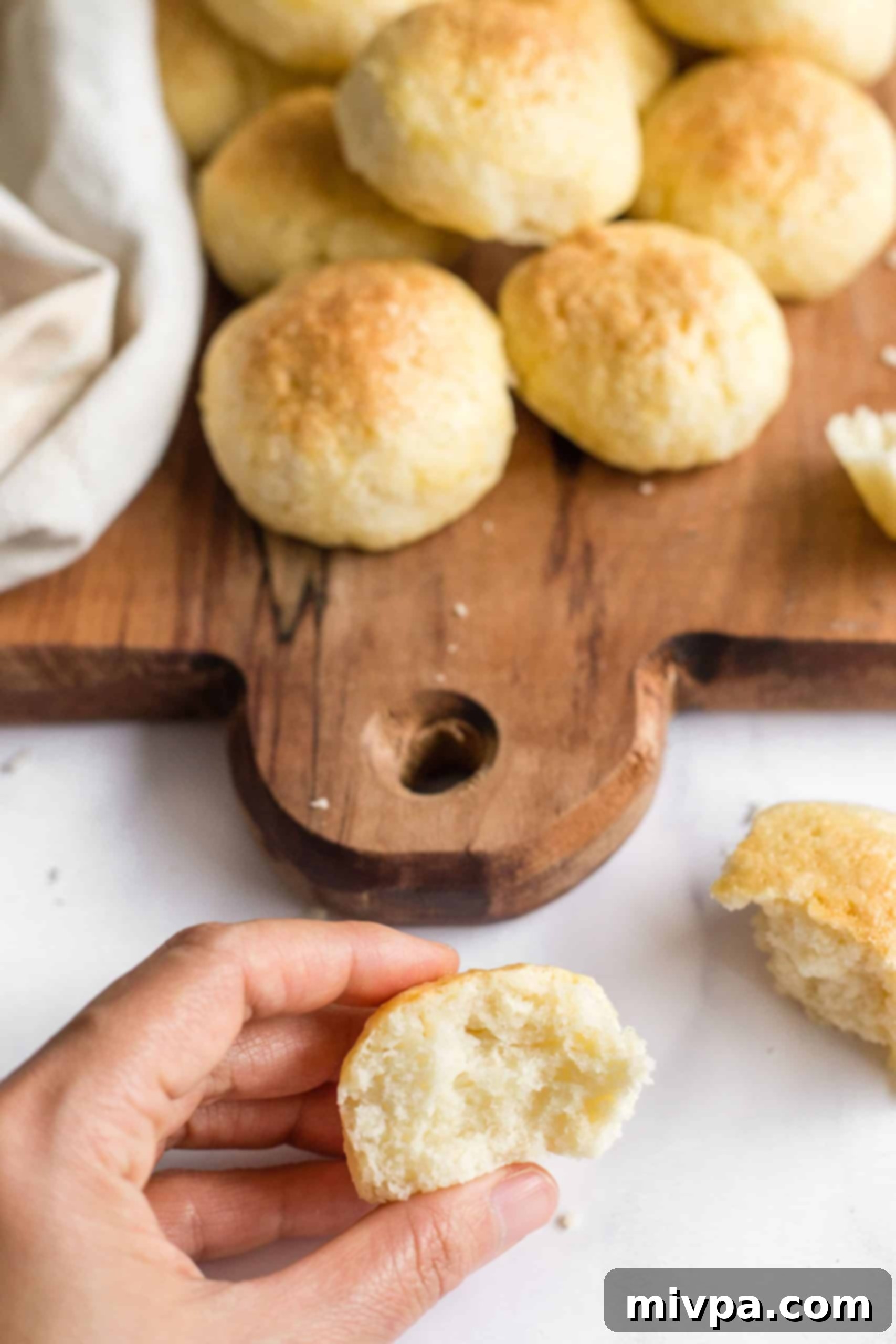 A hand gently tearing a warm, soft gluten-free roll, revealing its fluffy interior.