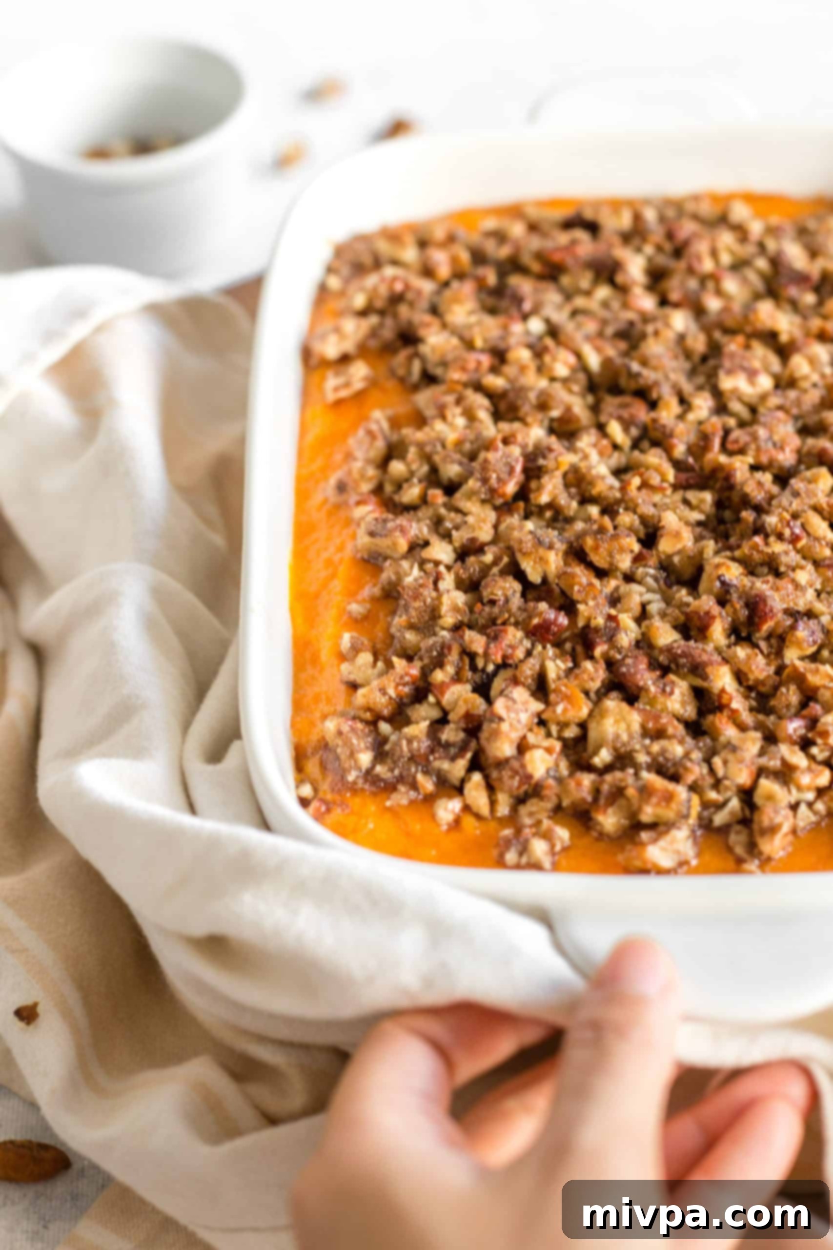 Gluten-Free Sweet Potato Casserole (Dairy-Free) Hand holding a casserole dish.