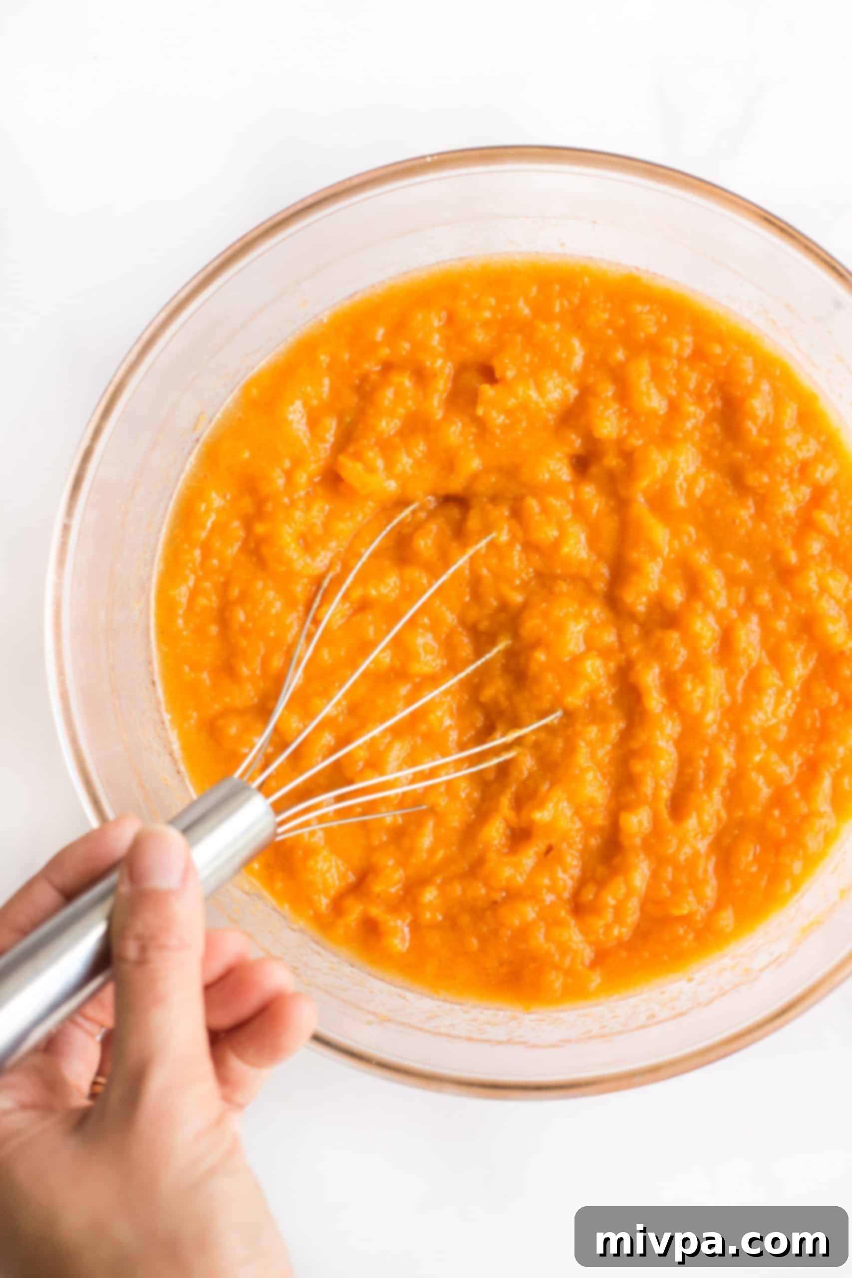 Dairy-Free Sweet Potato Casserole (Gluten-Free) Whisking mashed sweet potatoes in a large bowl.