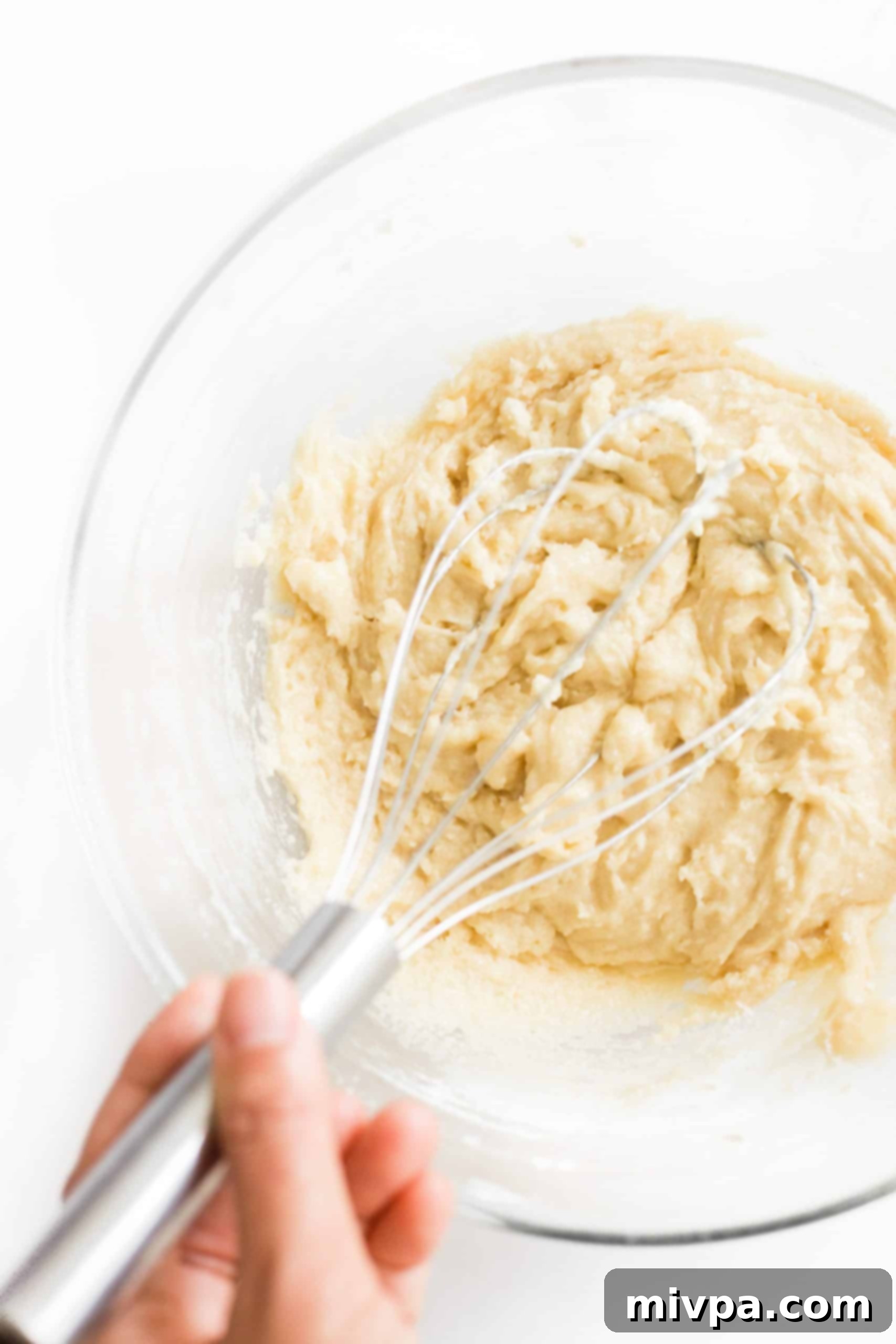 The process of combining wet and dry ingredients to form a soft gluten-free and dairy-free snickerdoodle cookie dough.