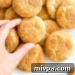 A close-up of a gluten-free and dairy-free snickerdoodle cookie with a light cinnamon sugar coating on a plate.